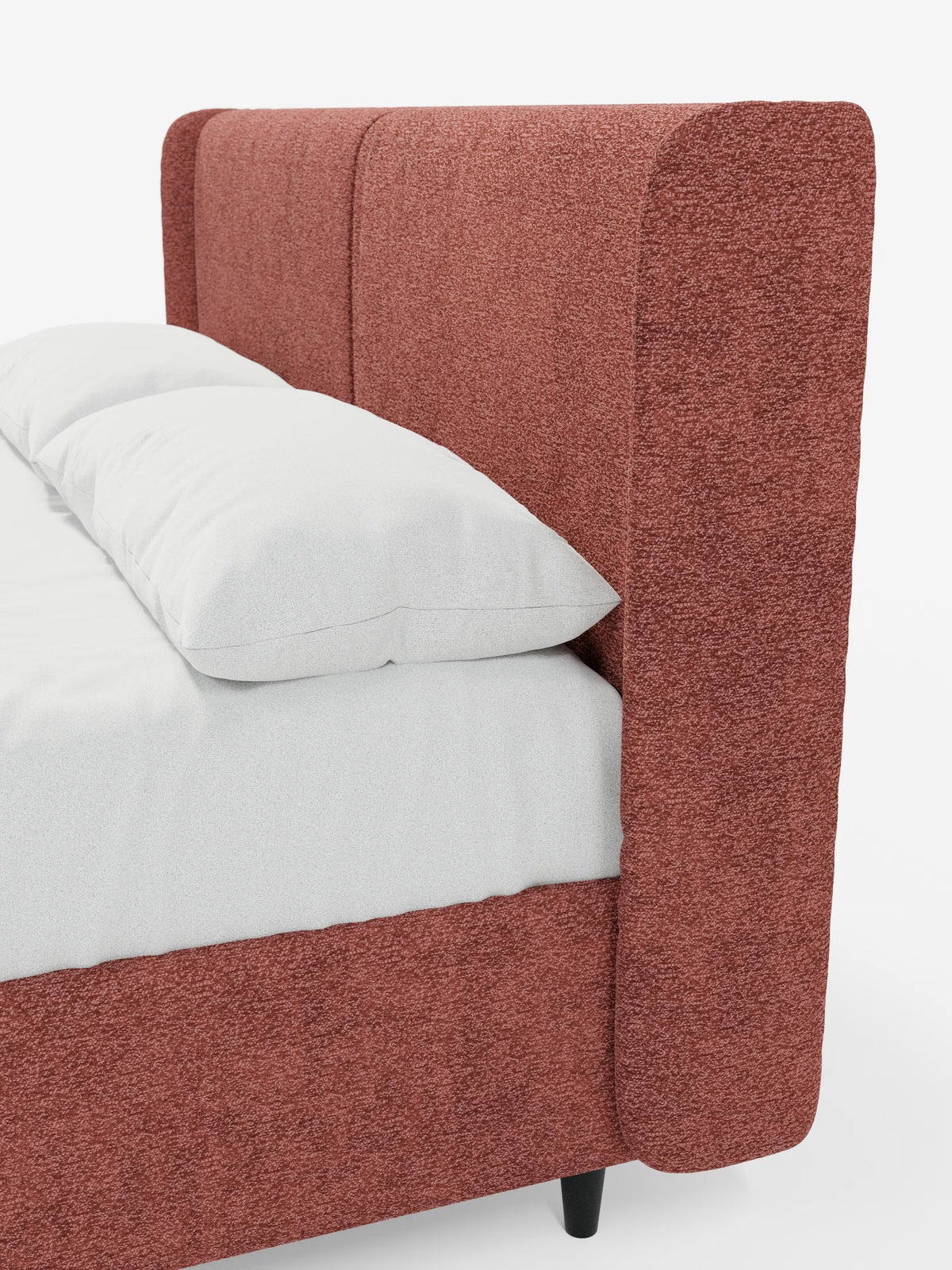Un primo piano del letto di design VALKIRIA con contenitore e testiera avvolgente di Letti.store mette in risalto la struttura e la testiera in tessuto Oeko-Tex® dalla trama rigata e dal colore ruggine. Questo letto moderno è caratterizzato da una testiera alta e leggermente ricurva, con due morbidi cuscini imbottiti e biancheria da letto bianca, che esalta il design contemporaneo su uno sfondo bianco a tinta unita. Le corte gambe nere ne completano il look elegante.