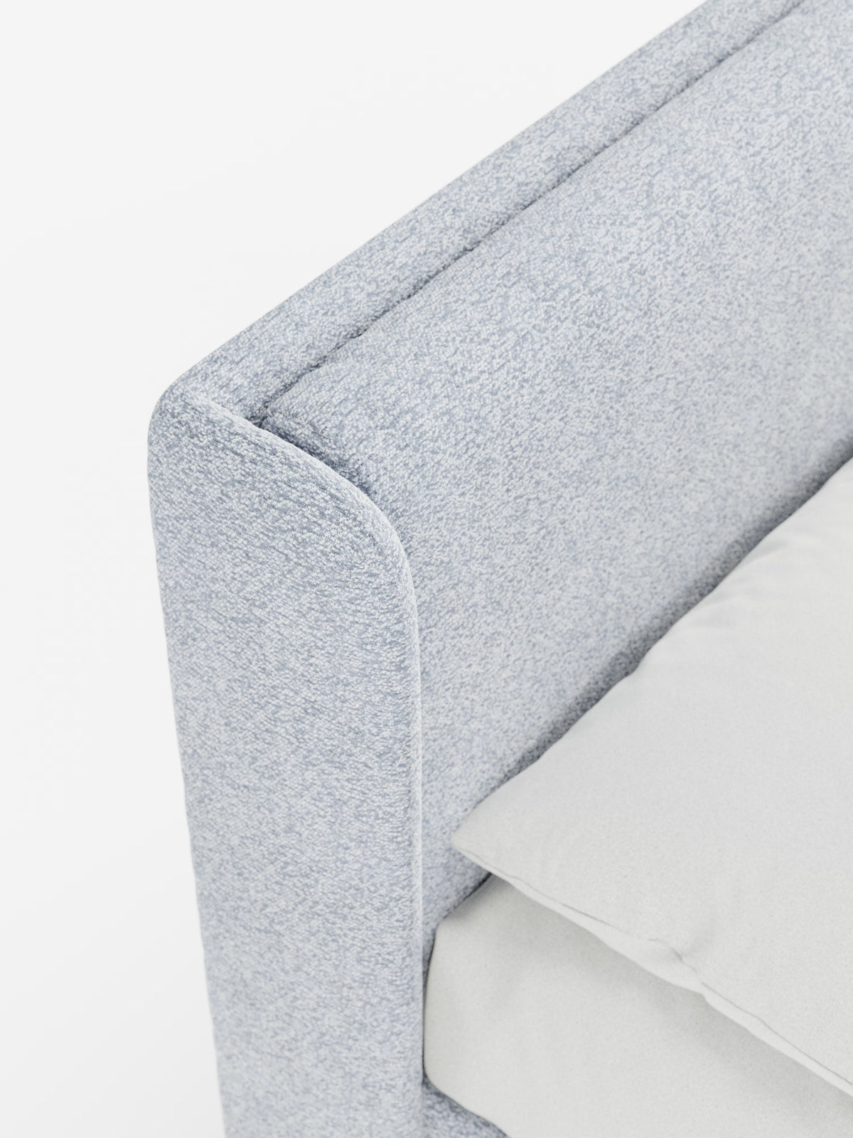 Primo piano del letto di design VALKIRIA di Letti.Il modello presenta un rivestimento in tessuto grigio chiaro certificato Oeko-Tex® sugli angoli arrotondati della struttura, con una parte del materasso ricoperta da un lenzuolo chiaro, il tutto su uno sfondo bianco brillante: un elegante esempio di design contemporaneo con la sua testiera avvolgente e i due cuscini imbottiti.