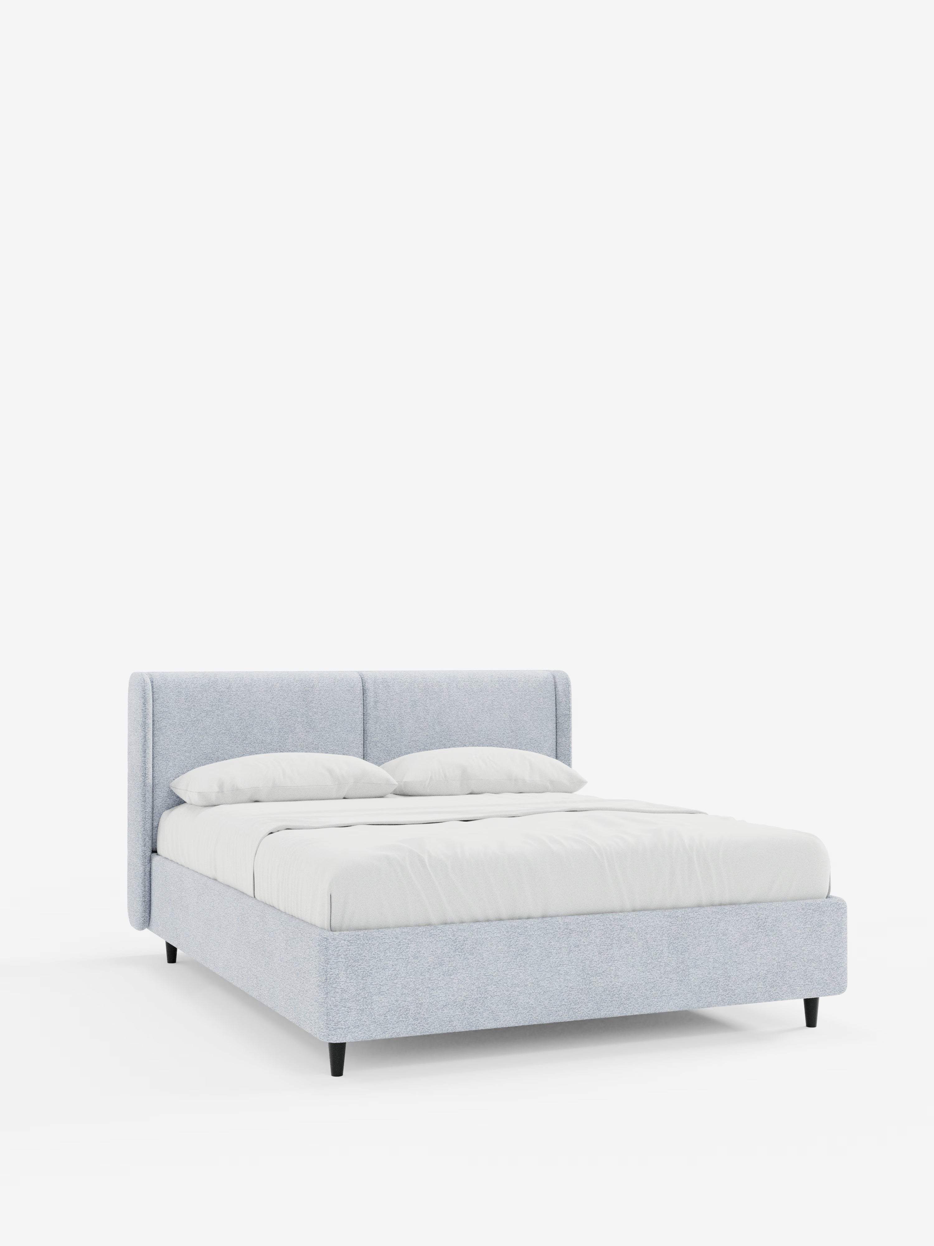 Il letto di design VALKIRIA con vano contenitore e testiera avvolgente di Letti.store si staglia su uno sfondo bianco, mettendo in risalto il suo look moderno e dal profilo basso. Questo letto contemporaneo presenta una struttura e una testiera imbottite in azzurro con 2 cuscini in tessuto Oeko-Tex®, accuratamente rivestito con biancheria da letto bianca — tra cui due cuscini e una trapunta — ed è sostenuto da gambe corte e scure.