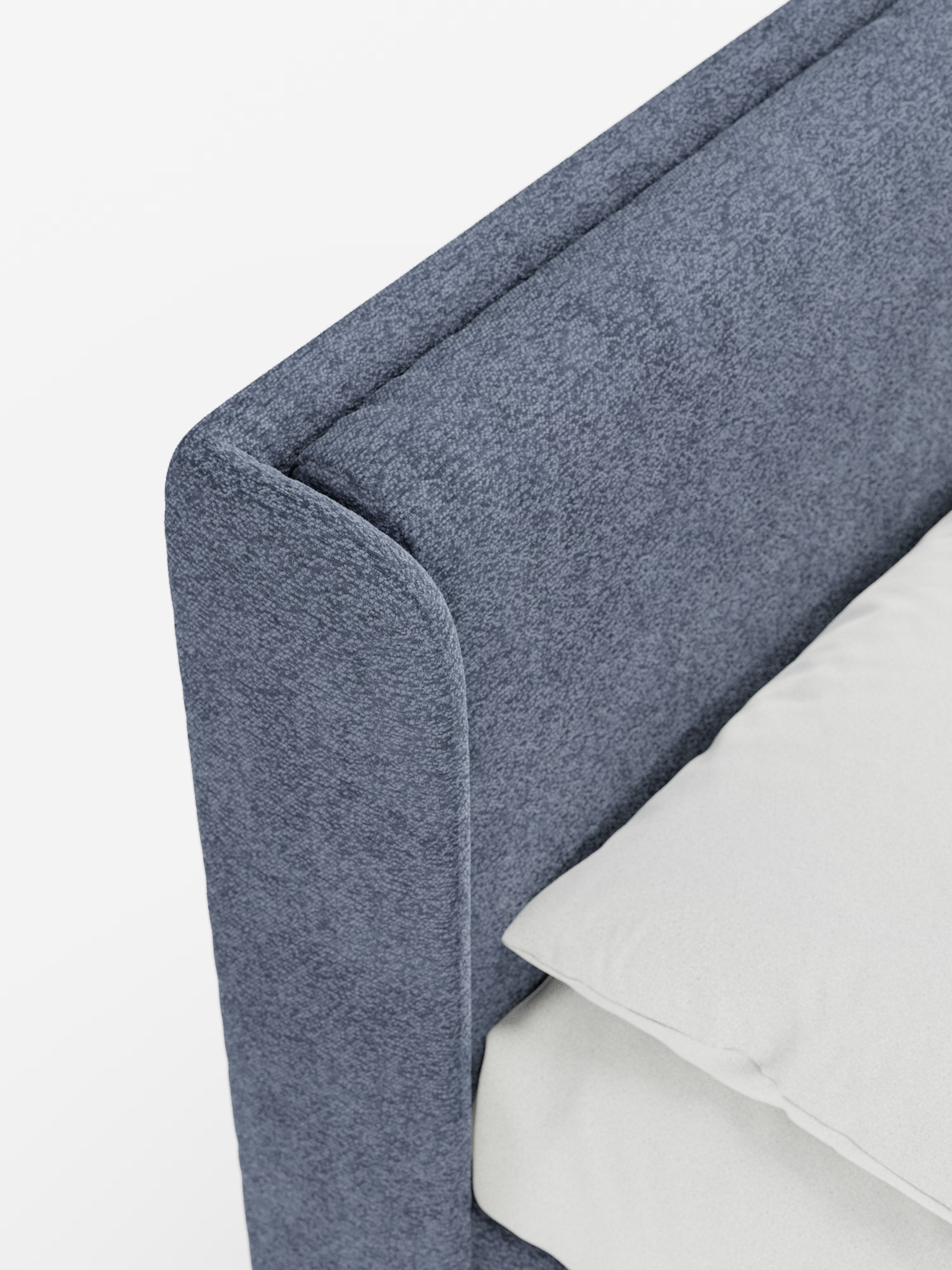 Primo piano del letto di design VALKIRIA con vano contenitore e testiera avvolgente di Letti.store, caratterizzato da testiera e struttura rivestite in tessuto blu-grigio testurizzato certificato Oeko-Tex®. Due cuscini imbottiti accentuano la testiera avvolgente, mentre un cuscino bianco e una parte del materasso bianco poggiano ordinatamente contro di essa. Lo sfondo minimalista, pulito e luminoso mette in risalto il design italiano contemporaneo di questo letto contenitore.