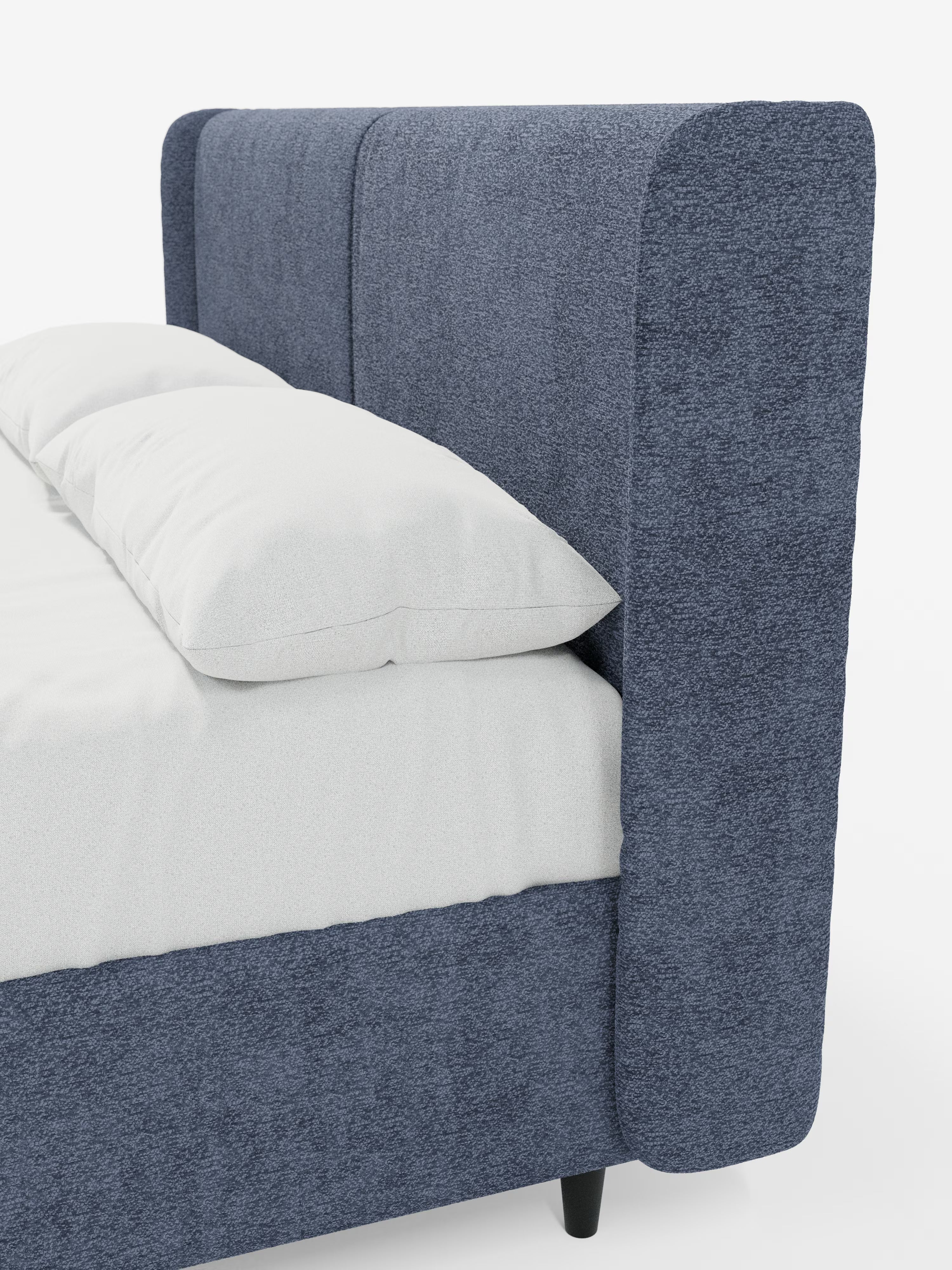 Un primo piano del letto di design VALKIRIA con vano contenitore e testiera avvolgente di Letti.store, caratterizzato da un’alta testiera imbottita blu dalla linea curva, con due cuscini imbottiti e un morbido tessuto Oeko-Tex®. Il letto moderno è abbinato a cuscini e biancheria da letto bianchi, che ne esaltano l’elegante design contemporaneo. Le gambe nere spuntano da sotto la struttura, il tutto su uno sfondo bianco a tinta unita.