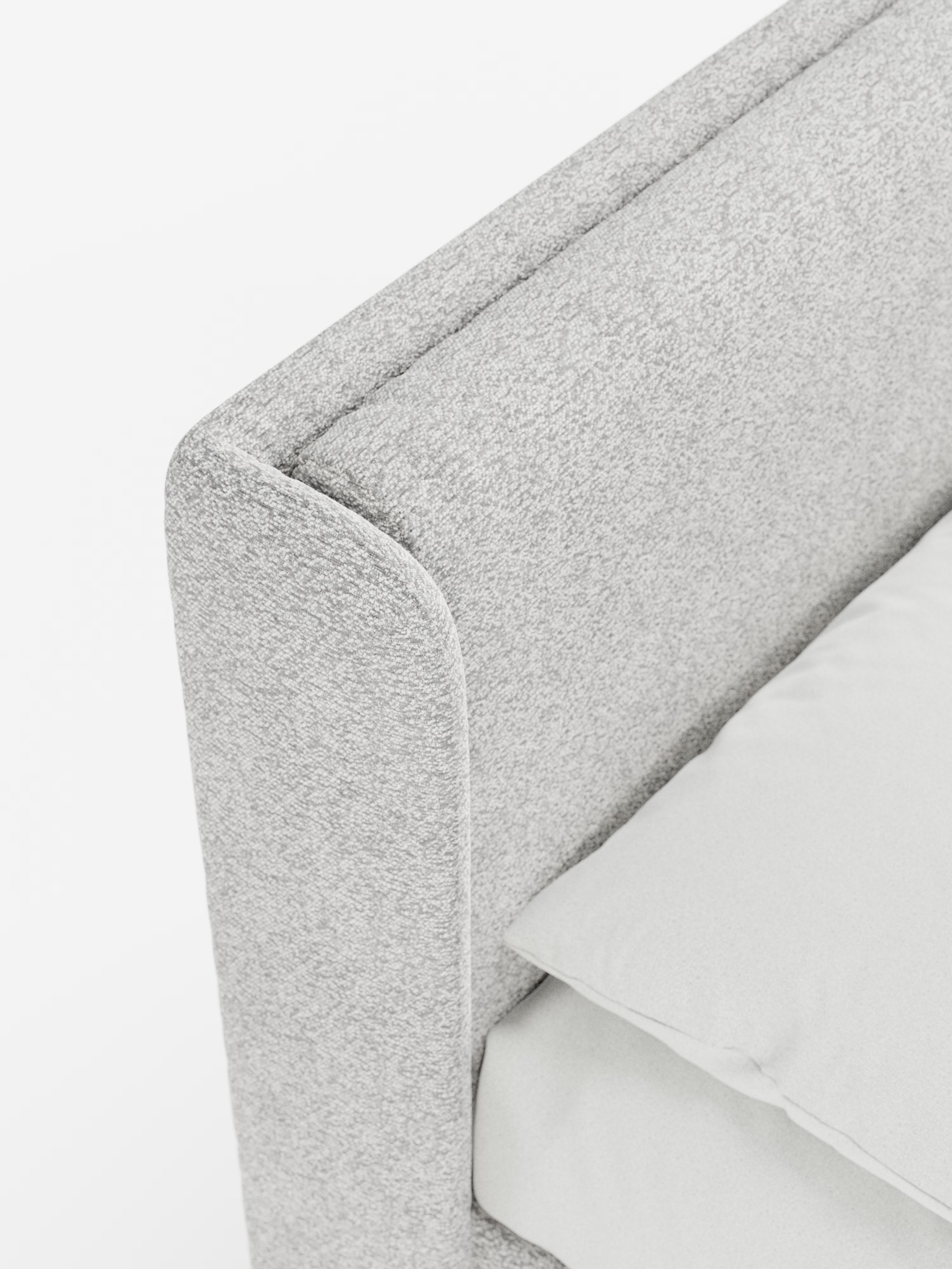 Primo piano del letto di design VALKIRIA con contenitore e testiera avvolgente di Letti.store, caratterizzato da un angolo imbottito grigio chiaro con due cuscini imbottiti in tessuto Oeko-Tex® e da una testiera spessa e avvolgente. Il letto, rifinito con cura e completato da un morbido cuscino bianco e da una coperta, mette in risalto le sue linee pulite e il suo design contemporaneo sullo sfondo bianco.