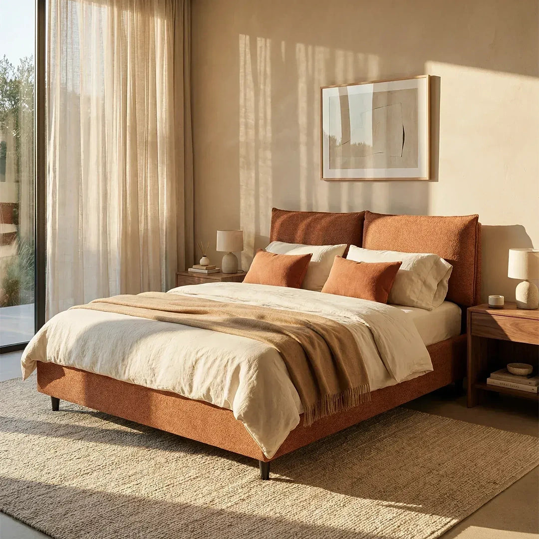 Una camera da letto moderna e luminosa è arredata con il letto imbottito ZAYRON con contenitore e morbidi cuscini regolabili di Letti.store, realizzato in tessuto Oeko-Tex®, rifinito con biancheria da letto color crema e abbinato a comodini in legno, lampade e un'opera d'arte astratta appesa sopra il letto.