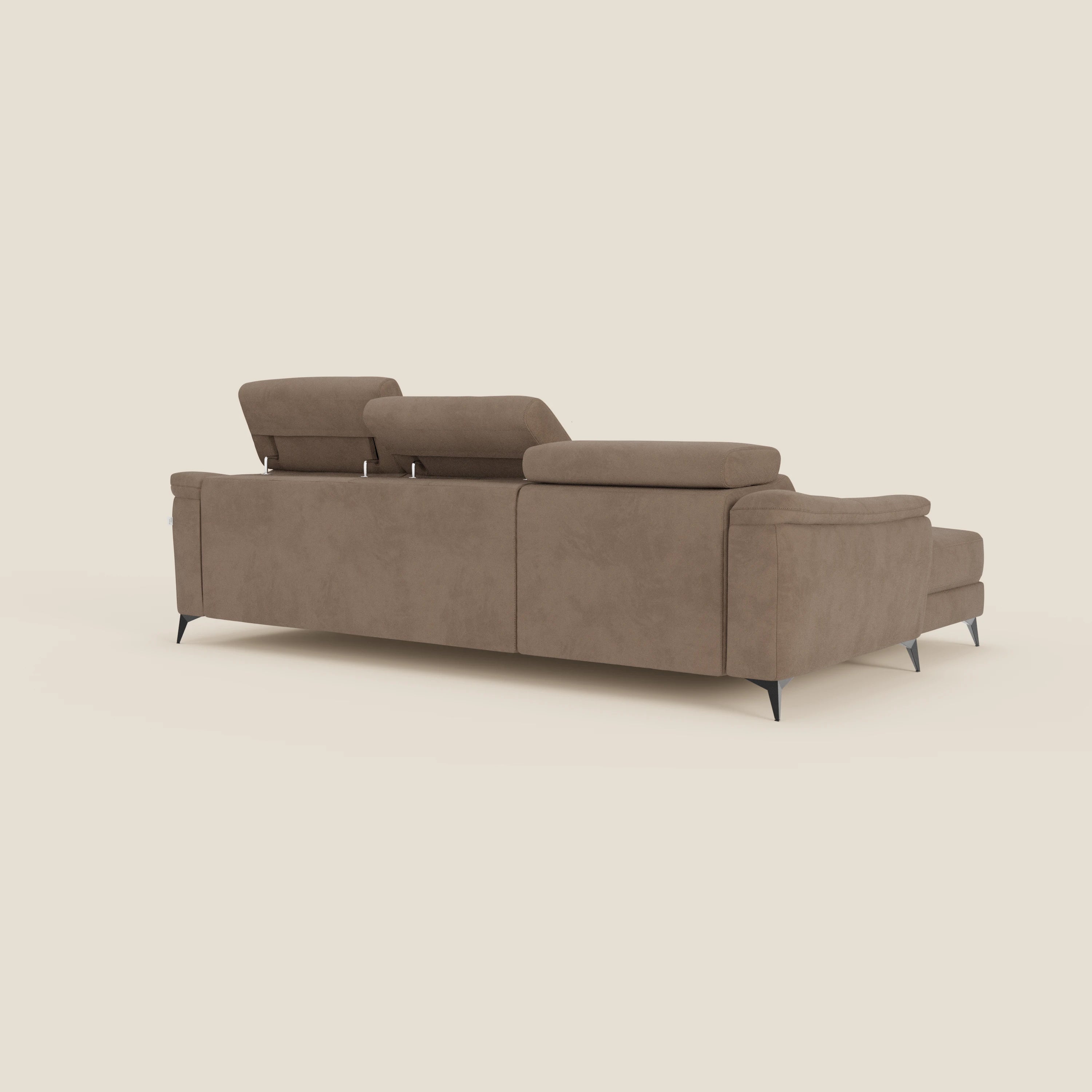 Arcos Divano con penisola di Divani.Store è presentato dal retro, con piedini alti, poggiatesta reclinabili, seduta estraibile e rivestimento in microfibra impermeabile T11 marrone su fondo beige chiaro.