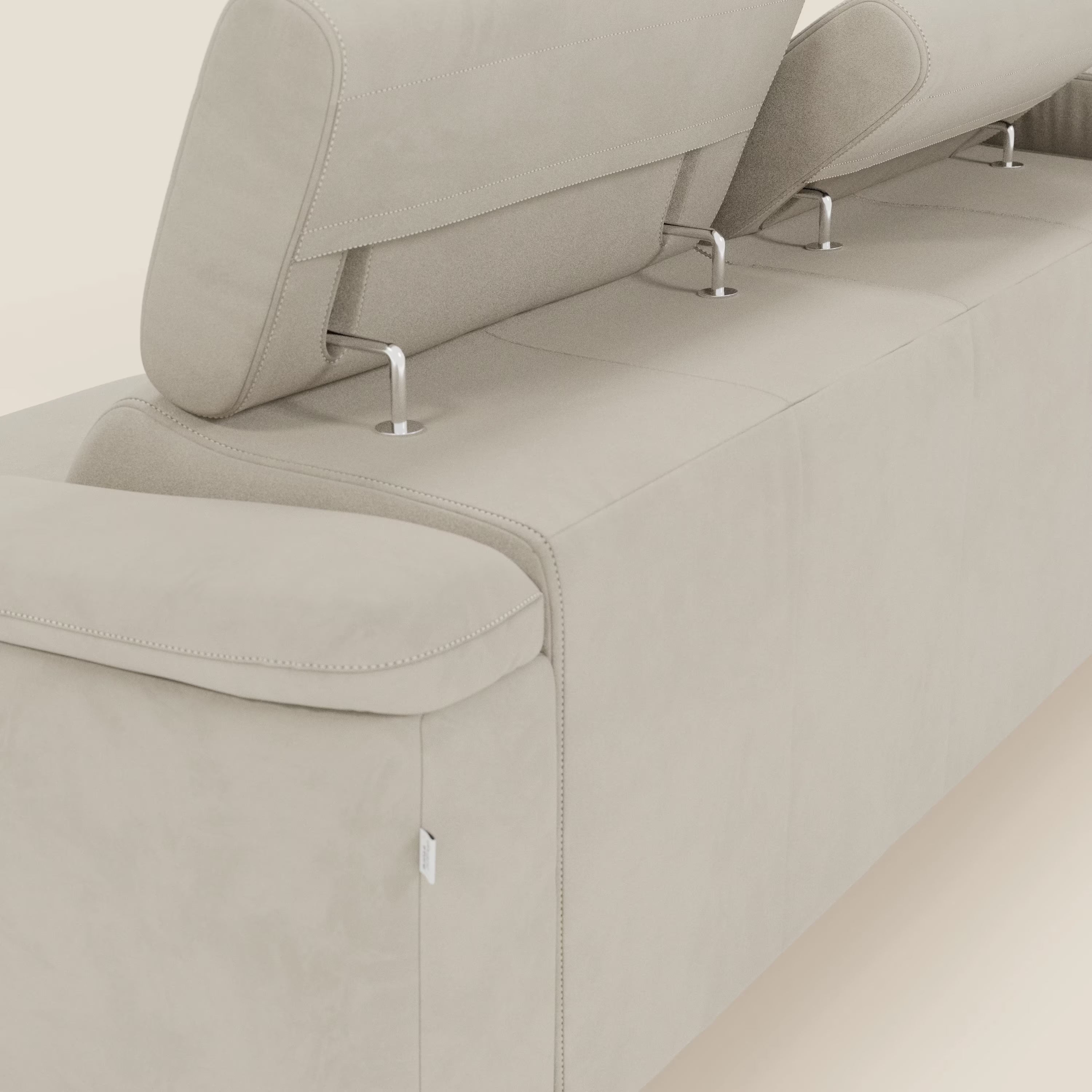 Primo piano dell'Arcos Divano con penisola di Divani.Store in microfibra impermeabile T11 panna, con gambe alte in metallo e poggiatesta regolabili. L'alta artigianalità italiana spicca su uno sfondo neutro.