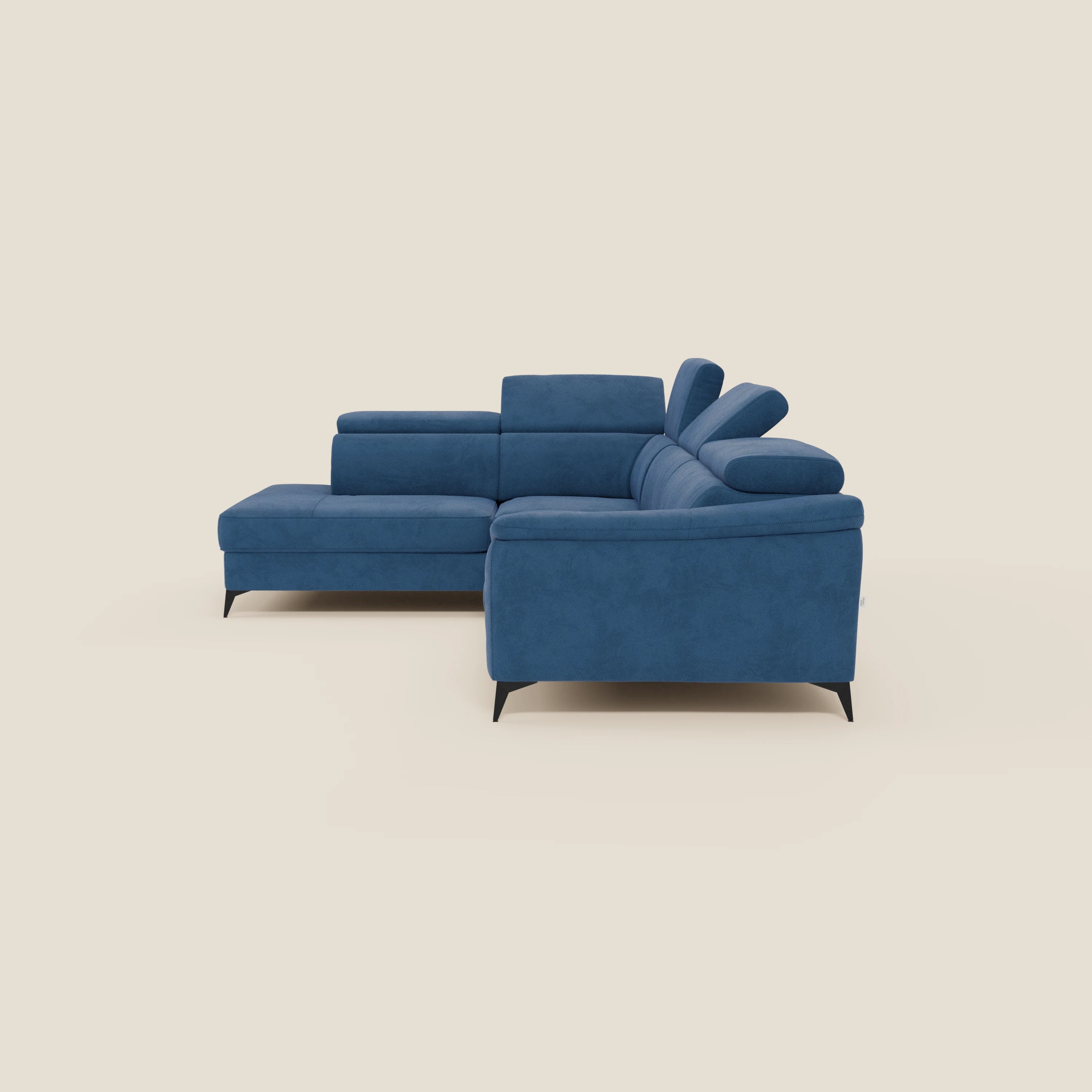 Il divano angolare Arcos di Divani.Store è presentato in microfibra impermeabile blu T11 con gambe alte nere, poggiatesta regolabili, sedute morbide e chaise longue, su uno sfondo beige chiaro per un look elegante e moderno.