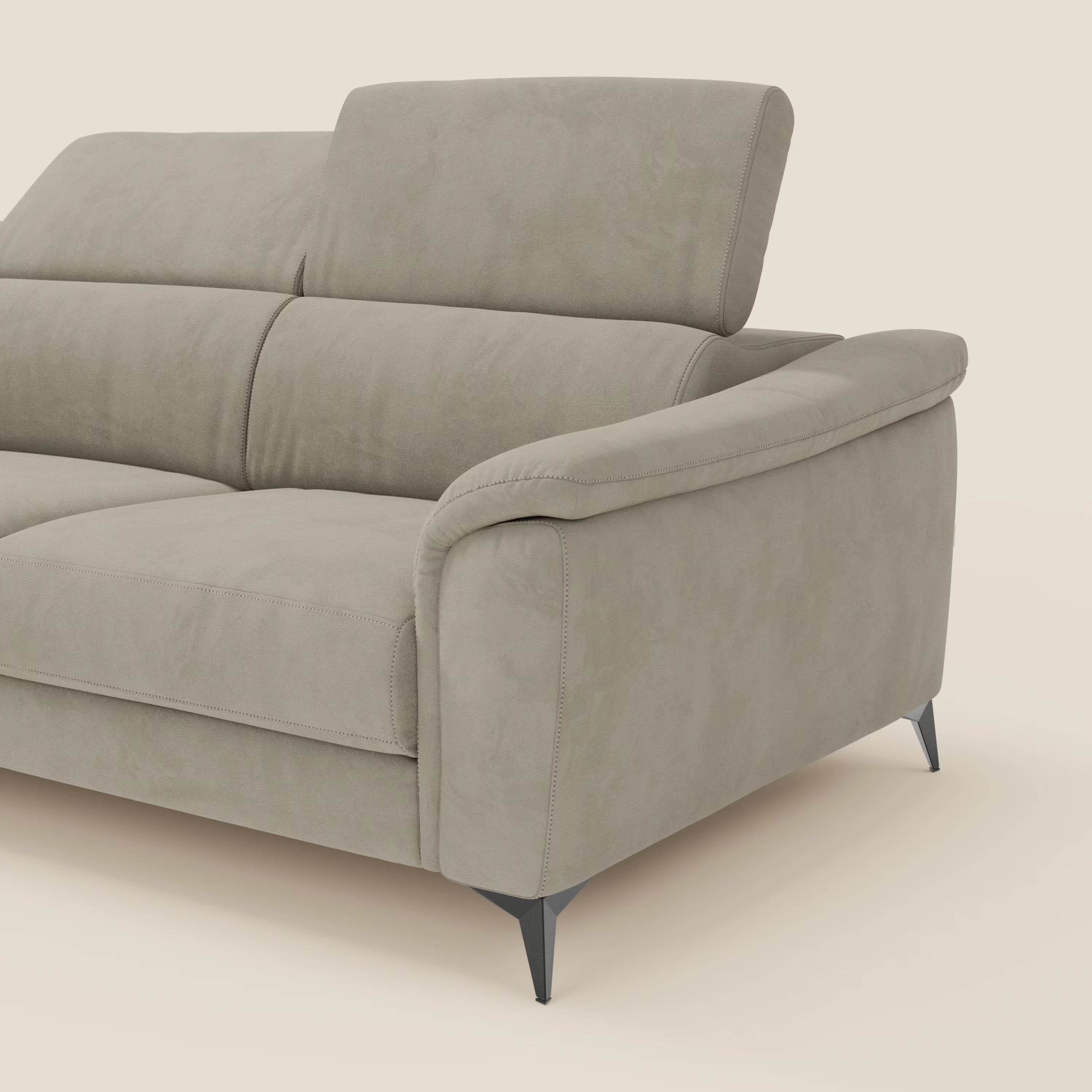 Il divano angolare Arcos di Divani.Store è caratterizzato da gambe alte, poggiatesta regolabili e microfibra impermeabile T11 taupe. Il suo design moderno comprende ampi braccioli, linee pulite e cuciture intelligenti. Solo una parte è visibile su uno sfondo beige.