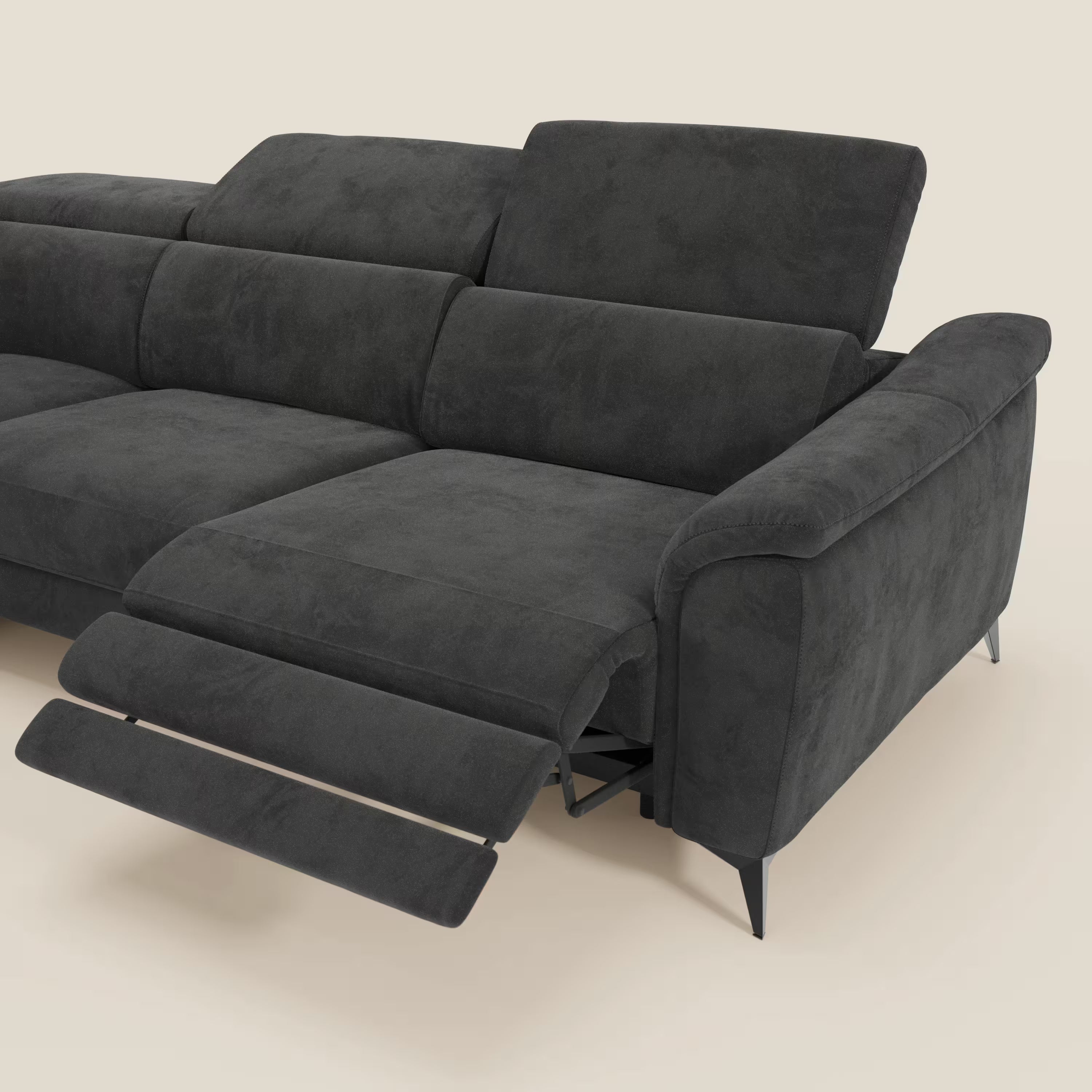 Arcos Divano angolare di Divani.Store è caratterizzato da gambe alte, poggiatesta regolabili e rivestimento in microfibra nera impermeabile T11. Le sue sedute morbide e il suo look moderno spiccano su uno sfondo beige chiaro, con la poltrona reclinabile estesa per mostrare due poggiapiedi.