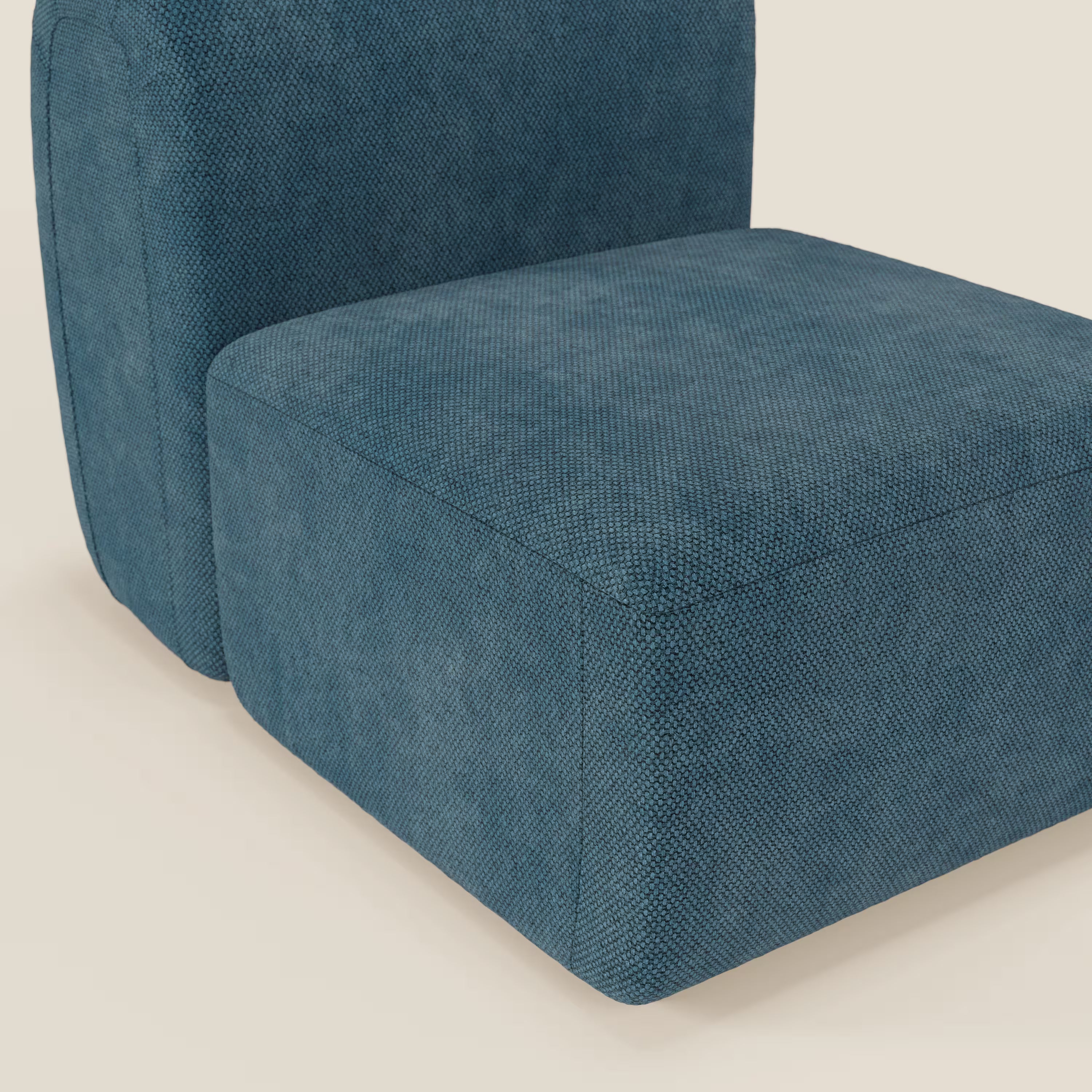 Primo piano del BonBon modulo centrale 70 cm - Grande Fratello edition petrolio di Divani.Store, rivestito in tessuto blu testurizzato, dalle linee pulite e dall'aspetto squadrato e minimalista. Sullo sfondo chiaro è visibile solo una parte della seduta e dello schienale inferiore.