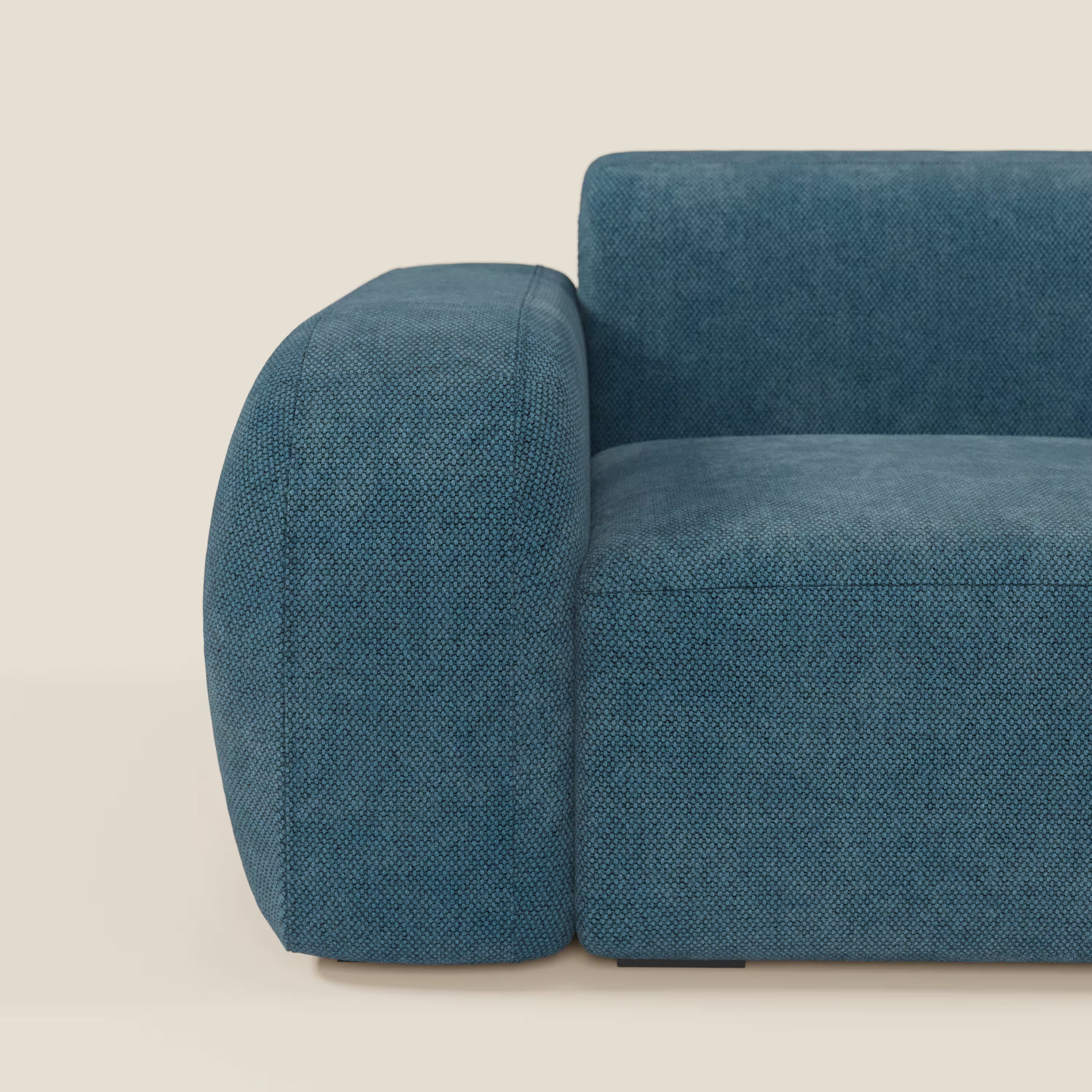 Un primo piano del BonBon modulo terminale 105 cm sinistro o destro - Grande Fratello edition petrolio di Divani.Store mostra la sua seduta morbida e il bracciolo arrotondato con un rivestimento blu intenso, che aggiunge uno stile accogliente e moderno su uno sfondo beige chiaro. Prodotto in Italia.