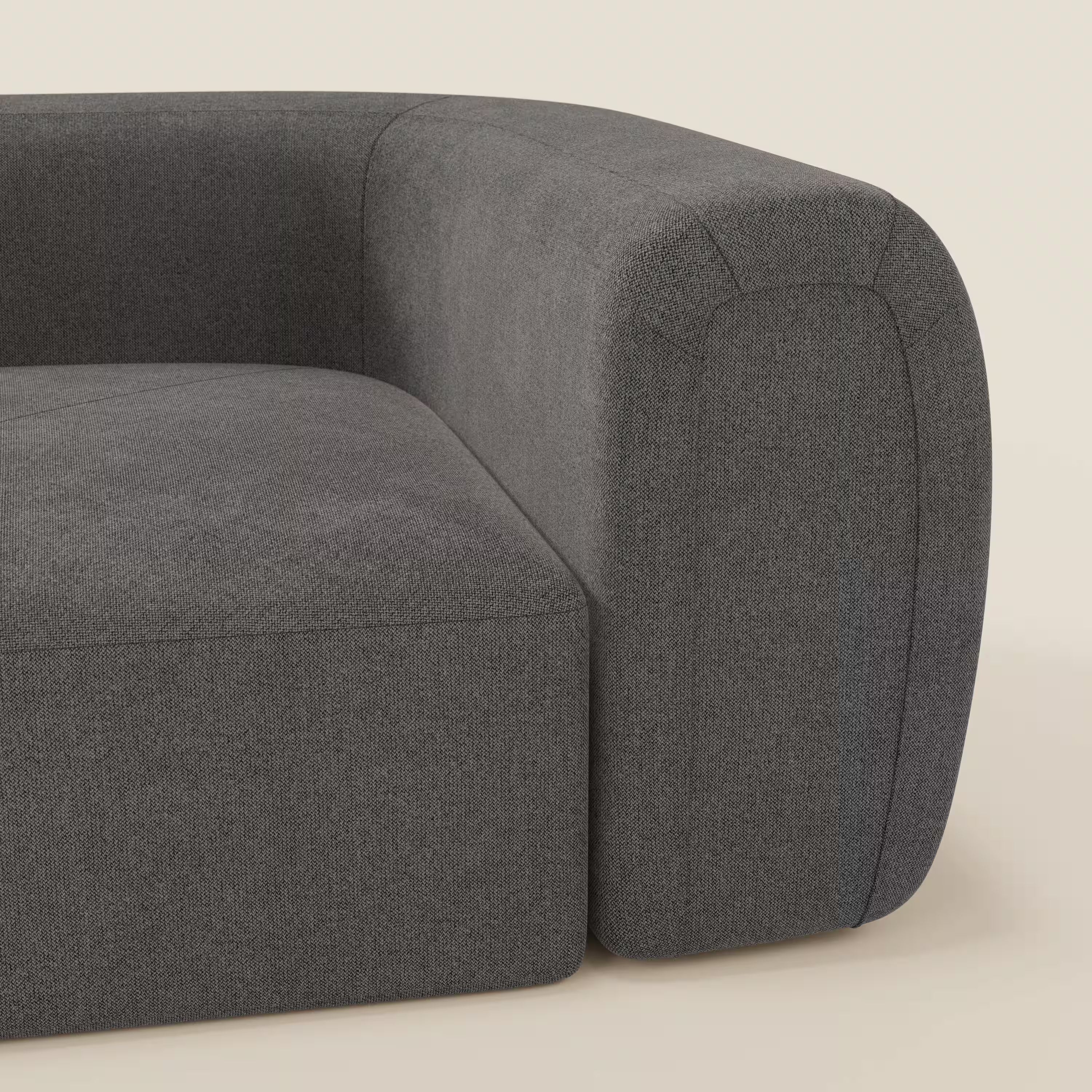 Primo piano di Bonbon Modulo angolare di Divani.Store, un moderno divano componibile in tessuto antracite T23 antimacchia, caratterizzato da schienale curvo, braccioli, linee pulite e cuscini in tessuto morbido su uno sfondo bianco sporco.