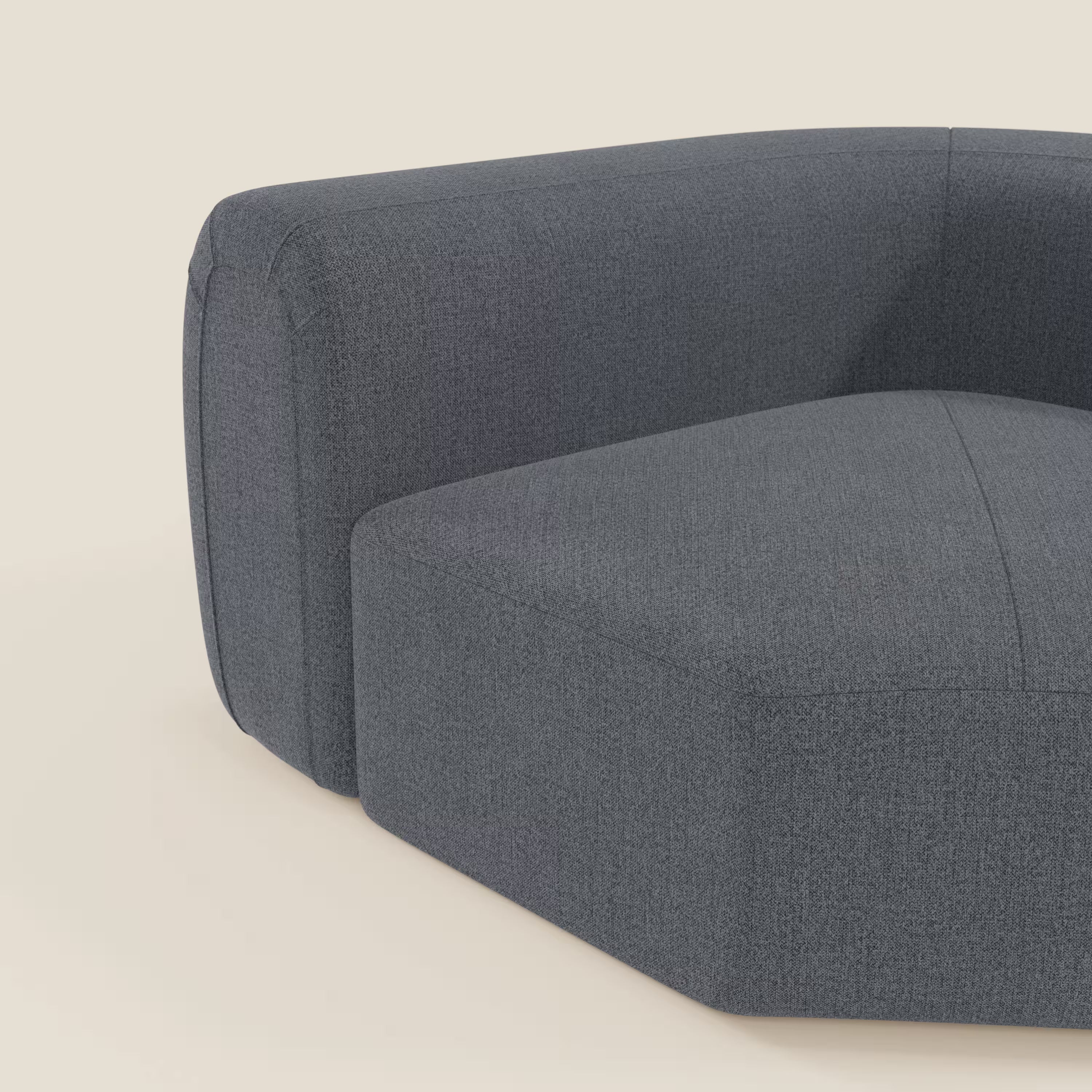 Primo piano di Bonbon Modulo angolare di Divani.Store, un divano moderno e modulare in tessuto antimacchia T23 blu grafite. Il design morbido e squadrato con bordi arrotondati mette in risalto il bracciolo destro e la seduta su uno sfondo beige chiaro.