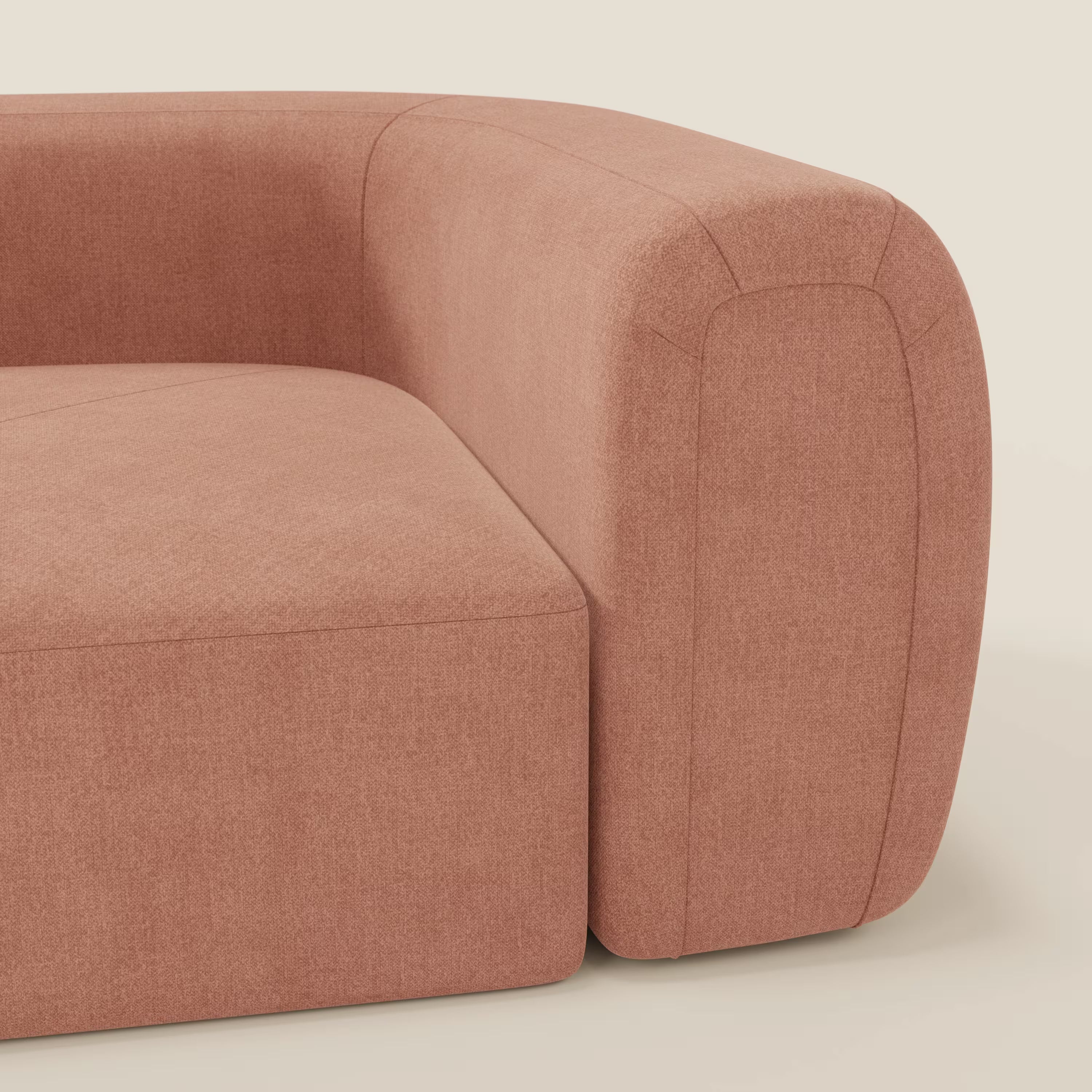 Primo piano di Bonbon Modulo angolare di Divani.Store, un moderno divano componibile in tessuto T23 pesca, facile da pulire, che mostra il bracciolo arrotondato e il cuscino di seduta con cuciture pulite su uno sfondo beige chiaro.