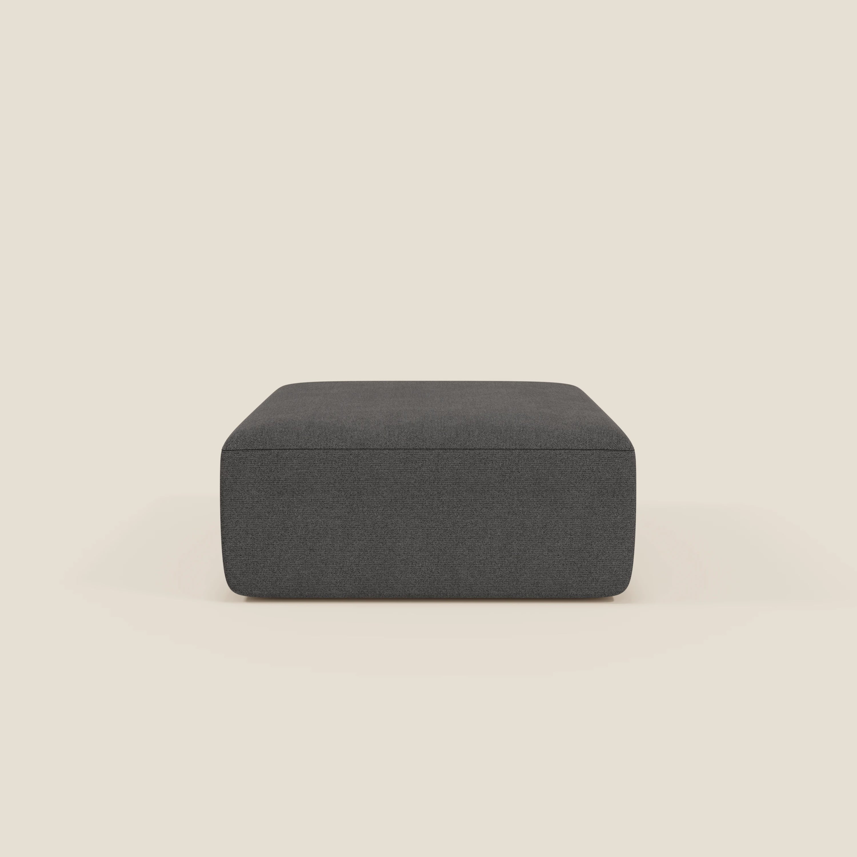 Il pouf divano modulare BonBon di Divani.Store, in tessuto antracite T23 antimacchia, è caratterizzato da un design rettangolare e minimalista, dalle linee pulite e senza gambe o decorazioni visibili, su sfondo beige chiaro.