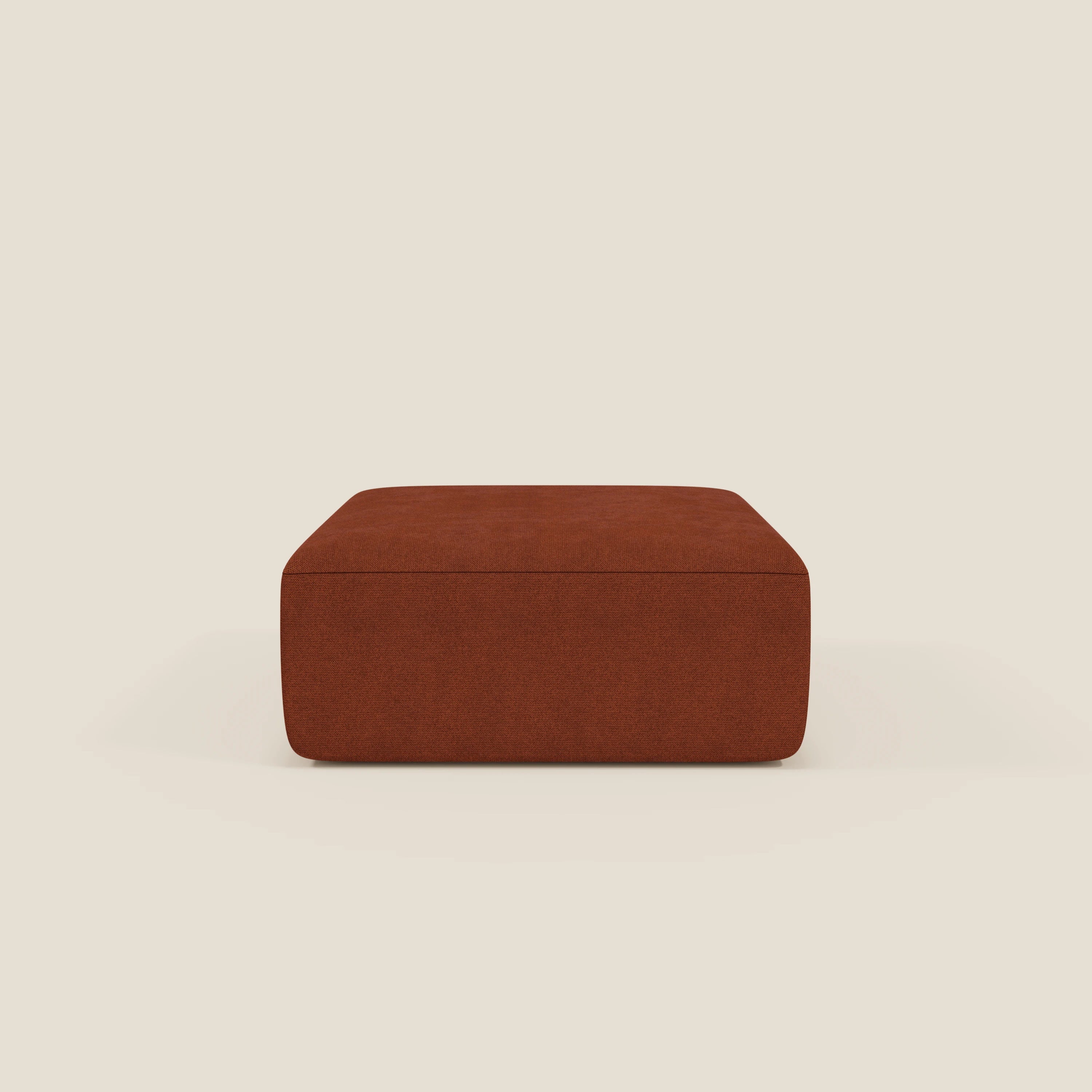 Il pouf BonBon di Divani.Store, presentato in tessuto antimacchia T23 color ruggine, è caratterizzato da un design moderno e squadrato, senza gambe o decorazioni visibili, su uno sfondo beige chiaro.