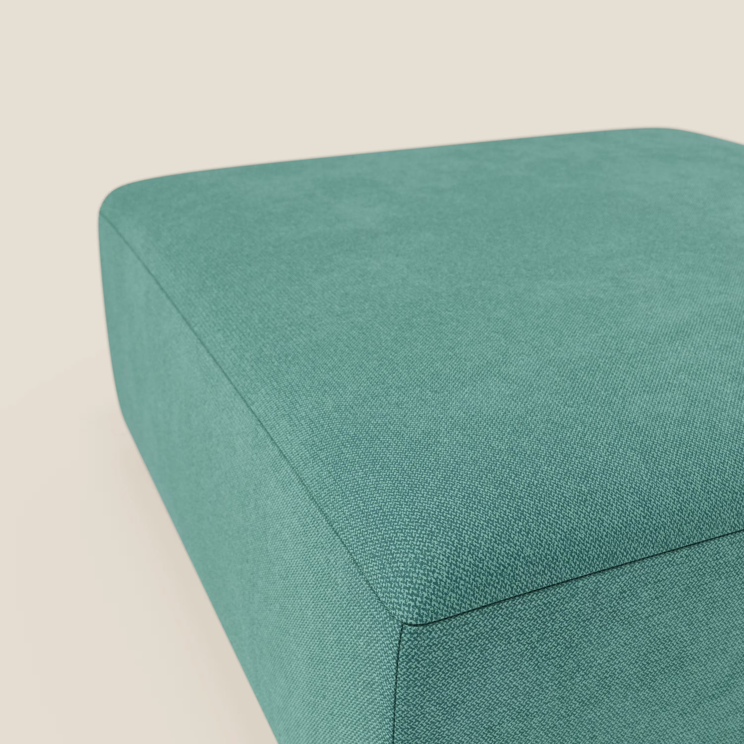 Primo piano del pouf divano modulare BonBon di Divani.Store, presentato in tessuto antimacchia T23 verde acqua. Di questo pouf rettangolare sono visibili solo la parte superiore e i due lati, su uno sfondo beige chiaro.