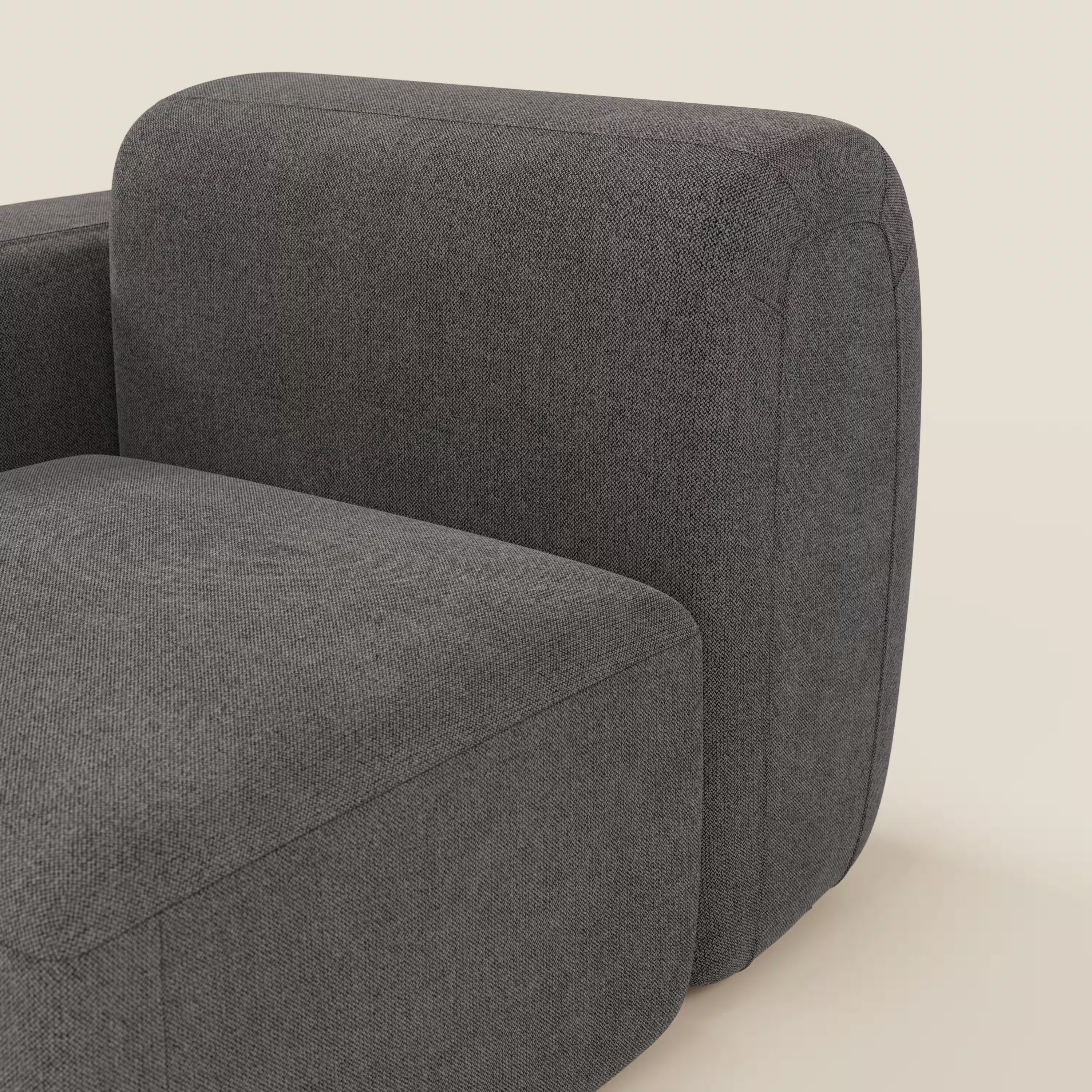 Un primo piano di BonBon modulo terminale 105 cm di Divani.Store in tessuto smacchiabile T23 antracite mostra il rivestimento morbido e strutturato e il bracciolo arrotondato su uno sfondo beige chiaro.