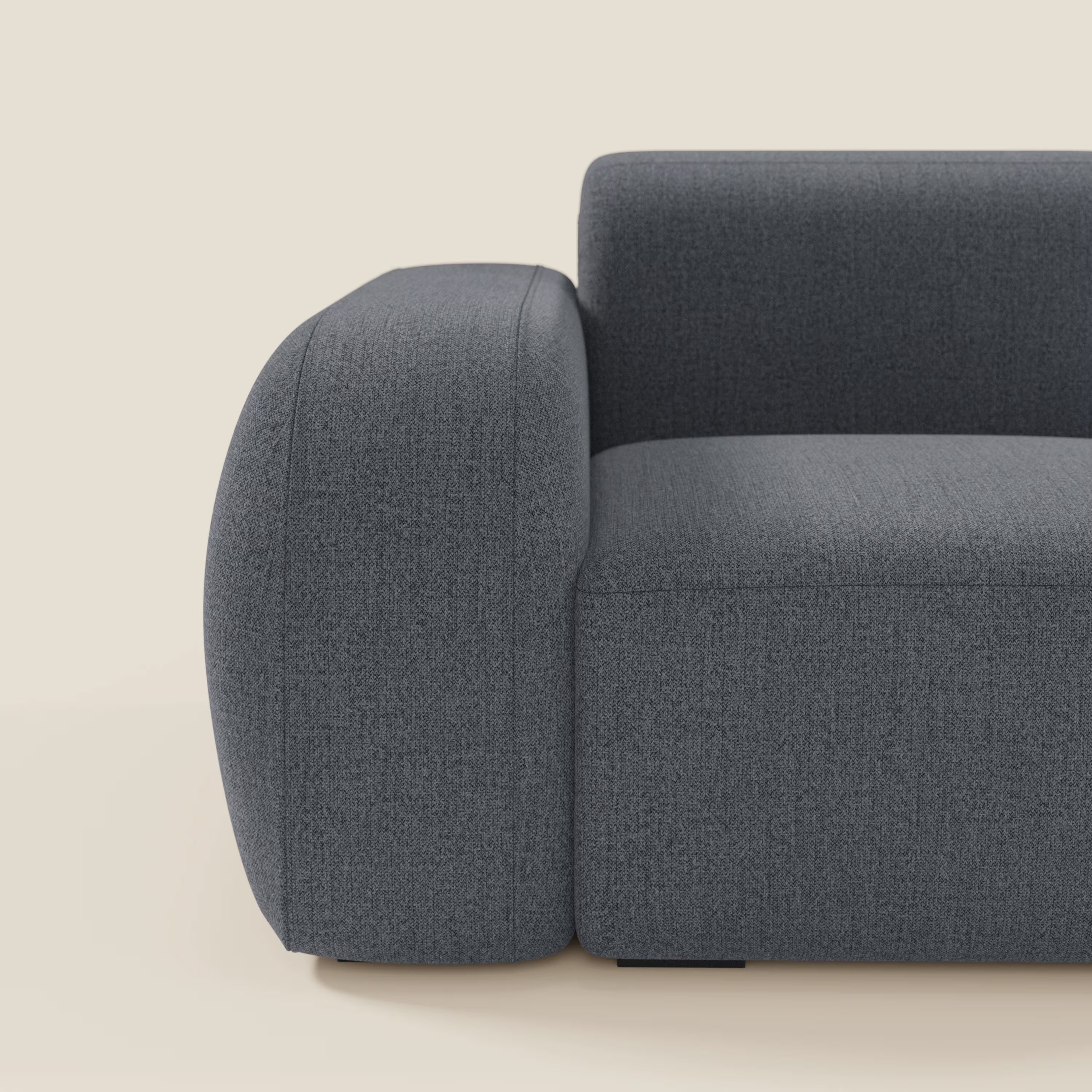 Una vista ravvicinata del modulo BonBon terminale 105 cm sinistro o destro in tessuto smacchiabile T23 blu grafite di Divani.Store, caratterizzato da bracciolo arrotondato, cuscini spessi ed elegante design contemporaneo su sfondo beige chiaro.