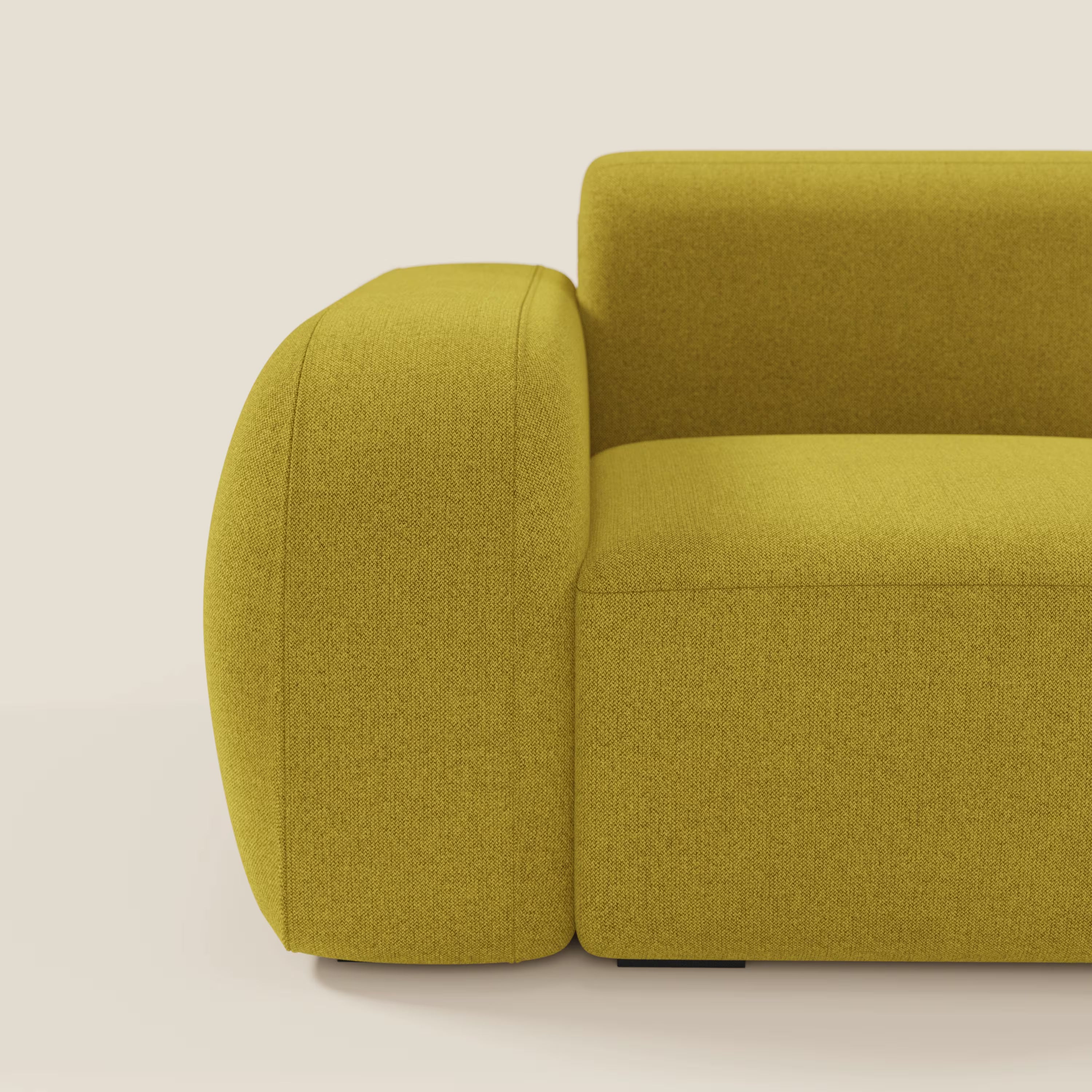 Un primo piano del BonBon modulo terminale 105 cm sinistro di Divani.Store in tessuto smacchiabile T23 giallo sole, che mostra l'ampio bracciolo sinistro arrotondato e la seduta morbida, su uno sfondo bianco sporco che ne evidenzia il colore deciso.