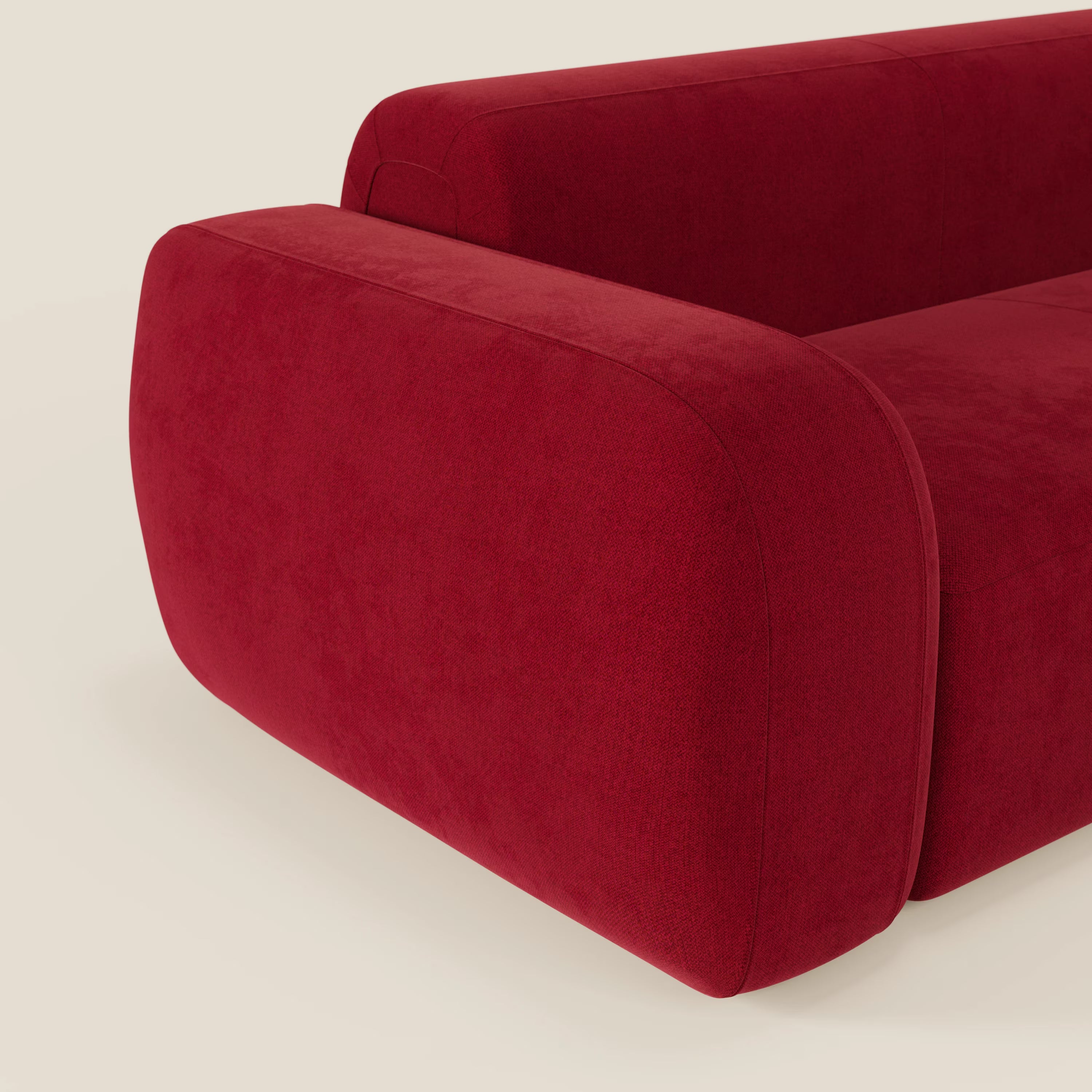 Il BonBon Divano modulare Lineare 220 di Divani.Store, presentato in tessuto antimacchia T23 bordeaux, è caratterizzato da ampi braccioli arrotondati e curve morbide per un look audace su uno sfondo beige. È visibile solo una parte del divano.