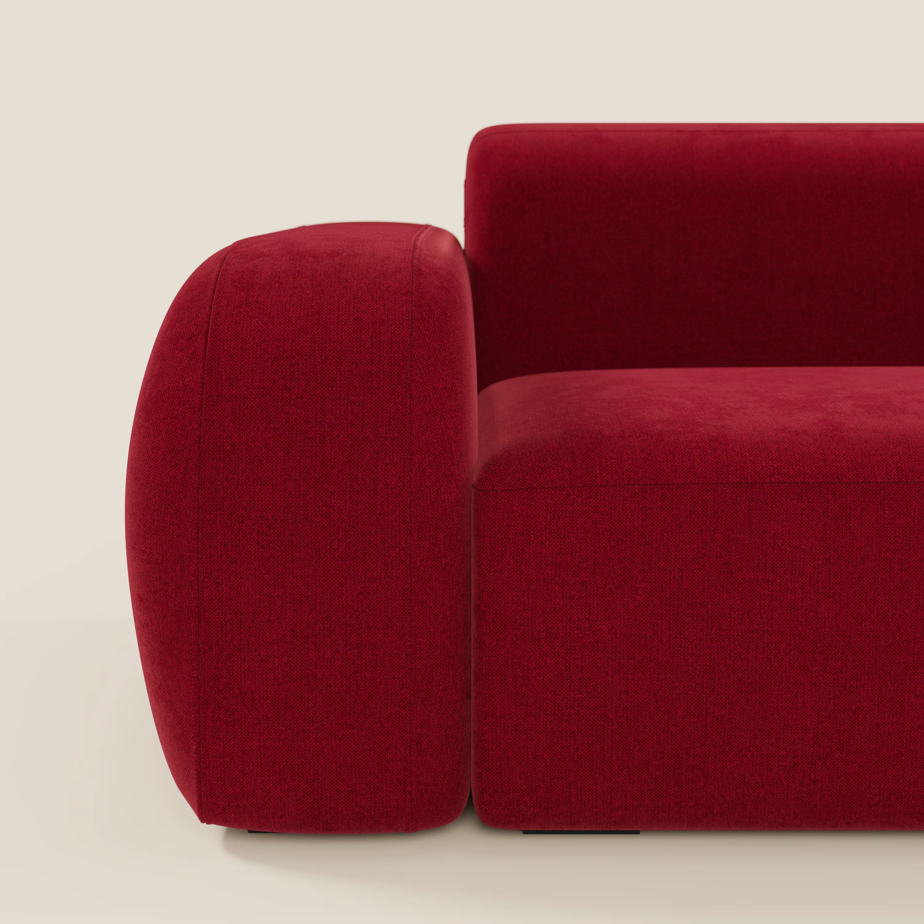 Primo piano del BonBon Divano modulare Lineare 220 di Divani.Store in tessuto smacchiabile T23 bordeaux, che mostra il bracciolo sinistro e la seduta e lo schienale lisci e arrotondati su uno sfondo bianco sporco.
