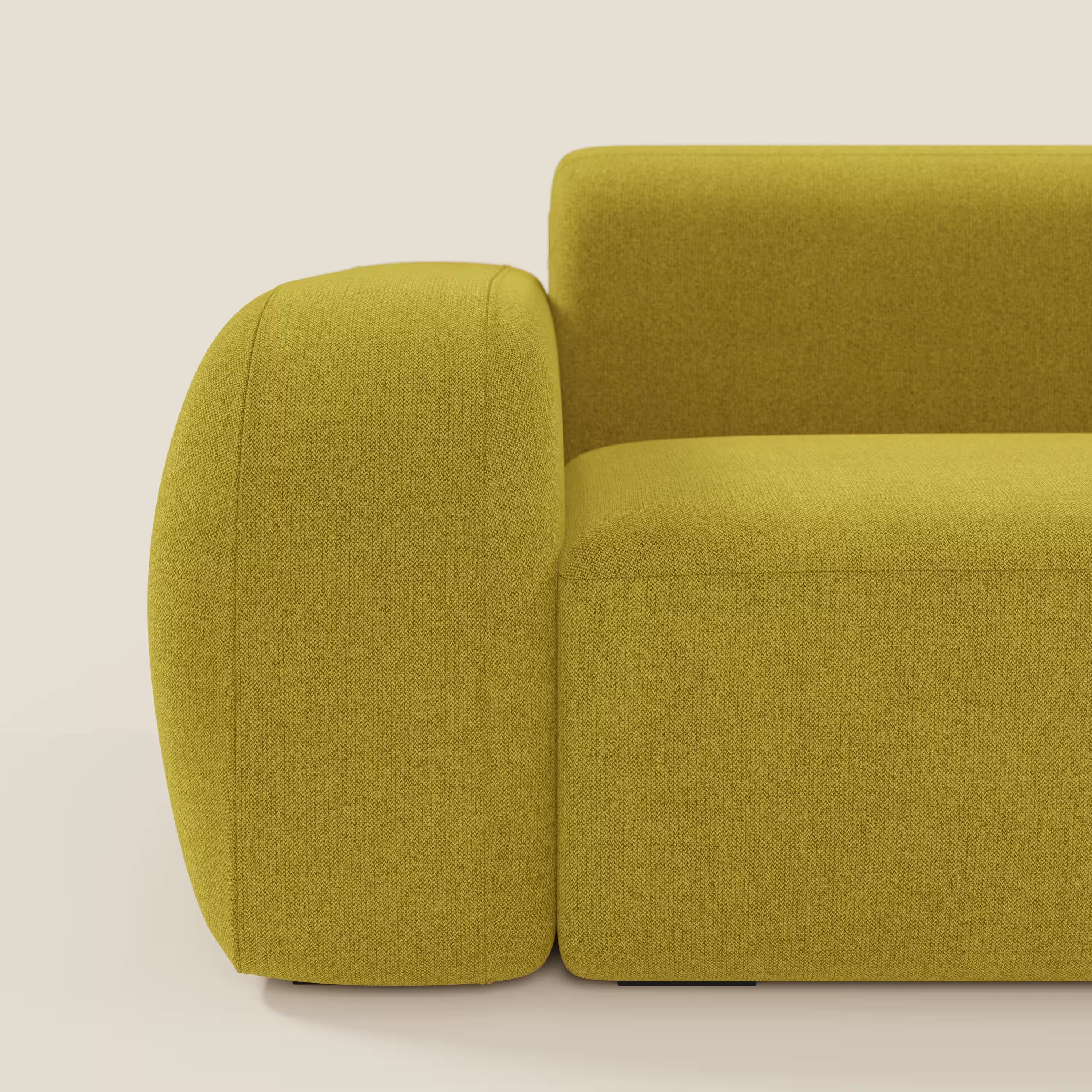Un primo piano del BonBon Divano modulare Lineare 220 di Divani.Store in tessuto smacchiabile T23 giallo sole. Il bracciolo e lo schienale, spessi e arrotondati, spiccano su uno sfondo beige, sottolineando il design audace e moderno del divano. Solo una parte è visibile.