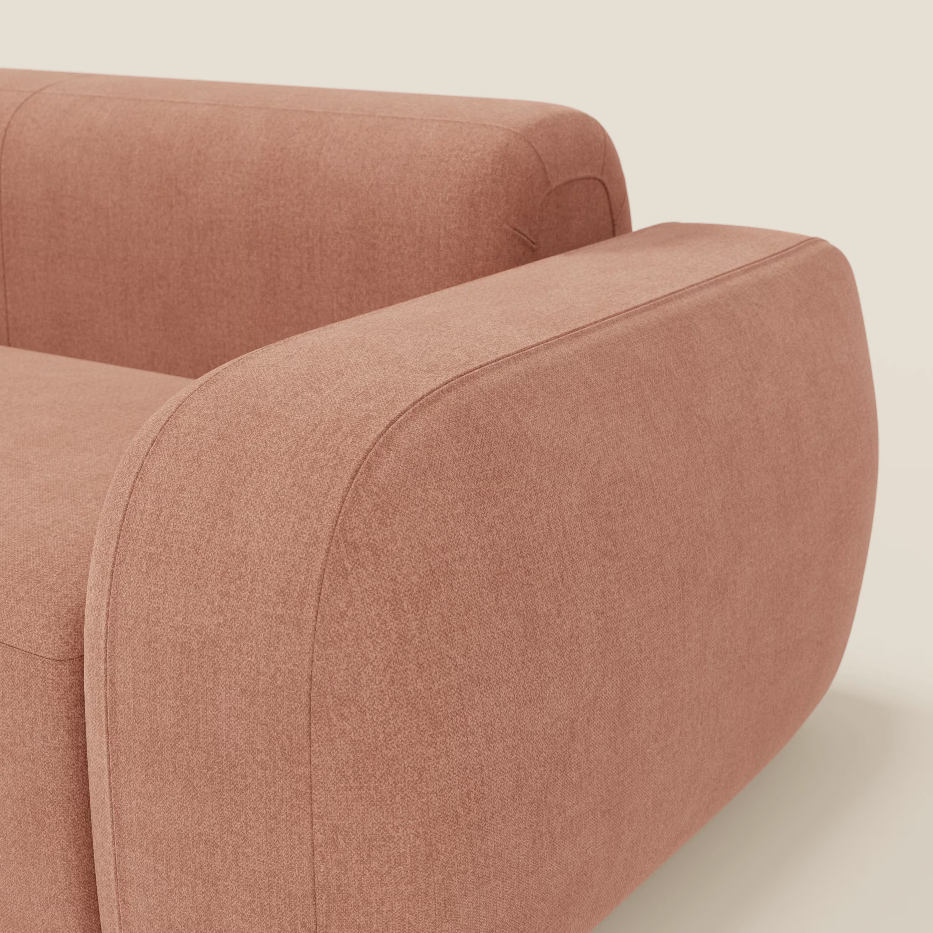 Primo piano del BonBon Divano modulare Lineare 220 di Divani.Store, caratterizzato da bordi arrotondati e dal morbido e smacchiabile tessuto T23 pesca, su uno sfondo bianco sporco. L'immagine evidenzia il bracciolo e la seduta.