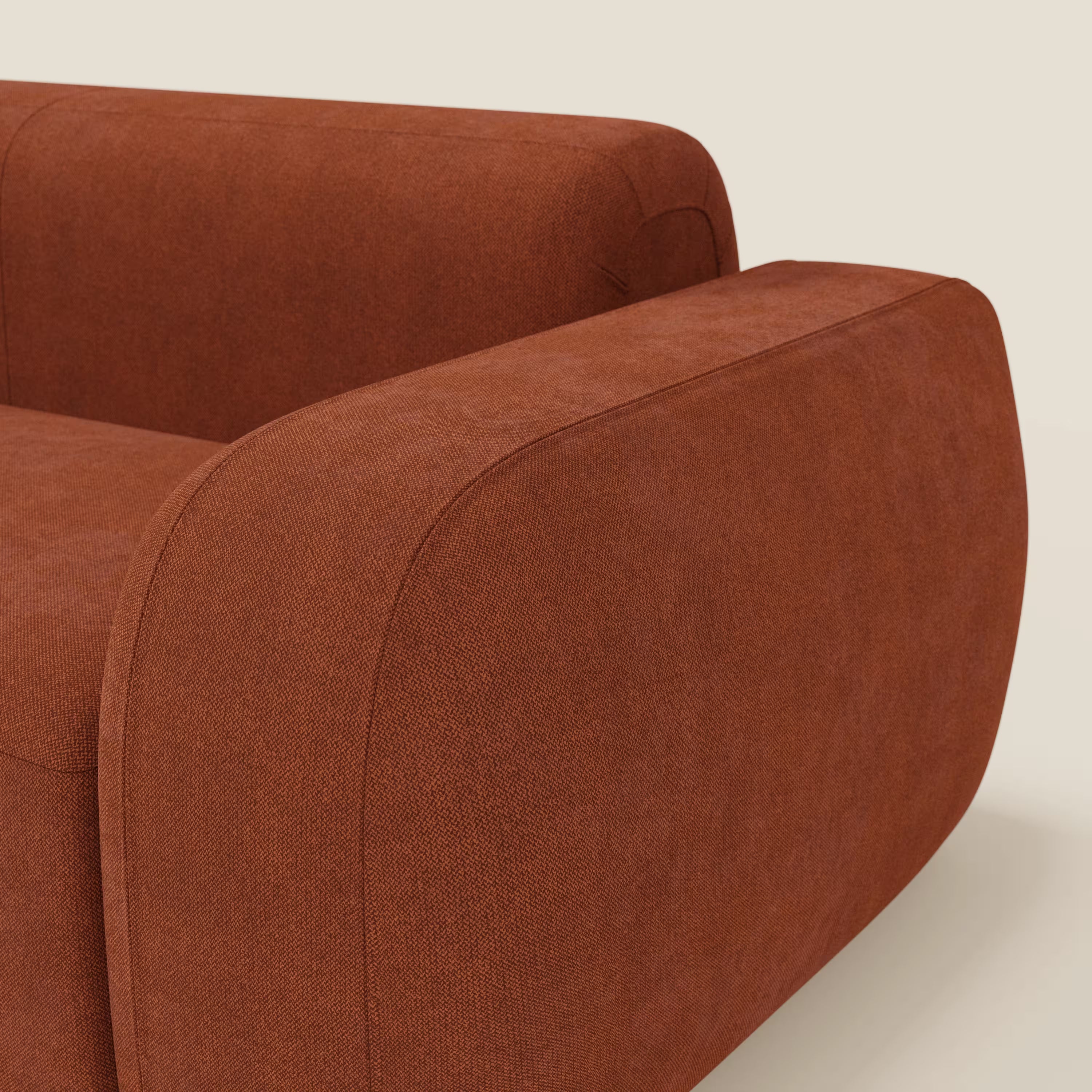 Primo piano di BonBon Divano modulare Lineare 220 di Divani.Store - un divano in tessuto antimacchia color ruggine con bordi morbidi e arrotondati e braccioli spessi - che mostra la sua tonalità calda e il suo design minimalista su uno sfondo beige chiaro.