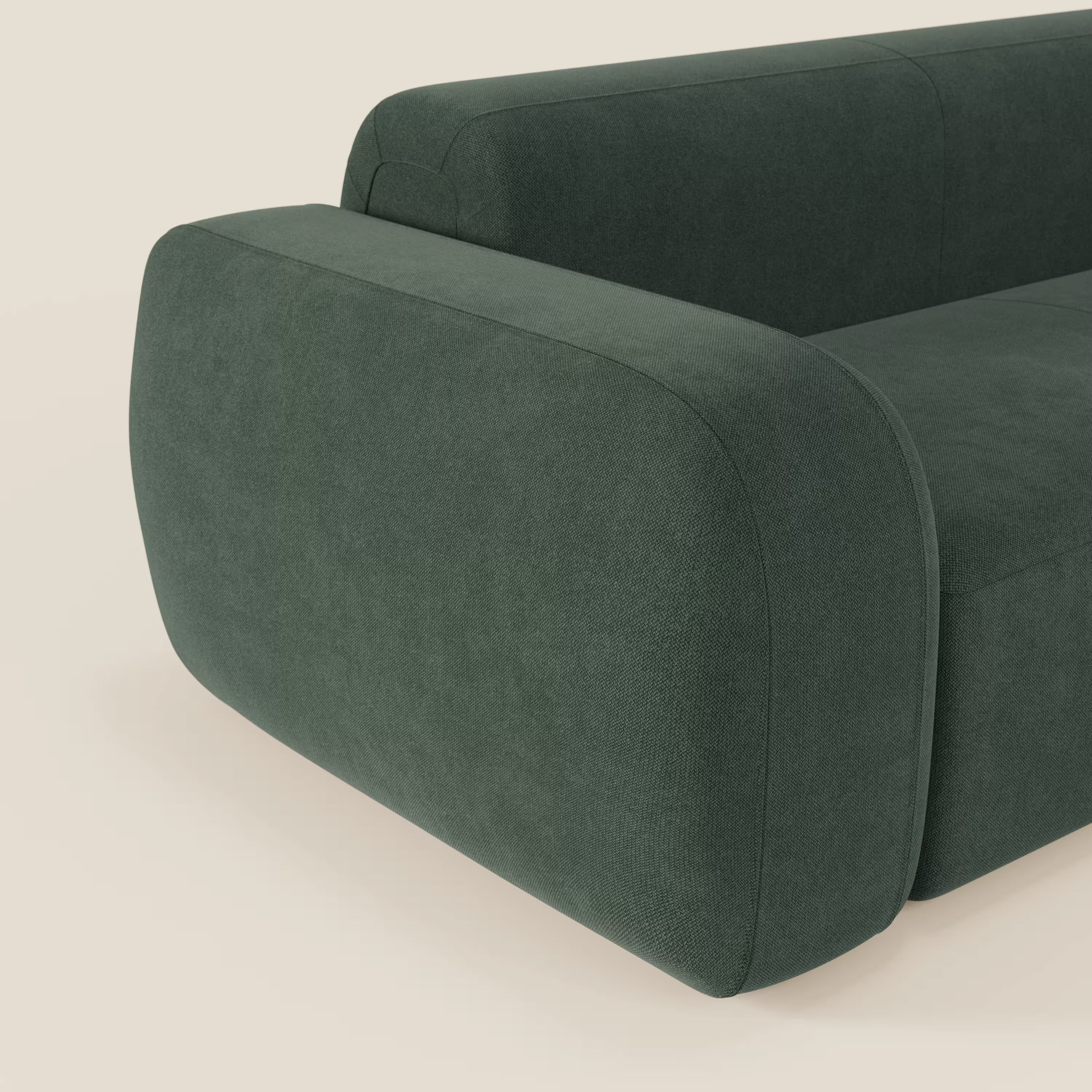 Primo piano del BonBon Divano modulare Lineare 220 di Divani.Store, caratterizzato dal tessuto smacchiabile T23 verde e dai braccioli spessi e arrotondati in un design minimalista. Solo una parte della seduta e del bracciolo è visibile su uno sfondo bianco sporco.