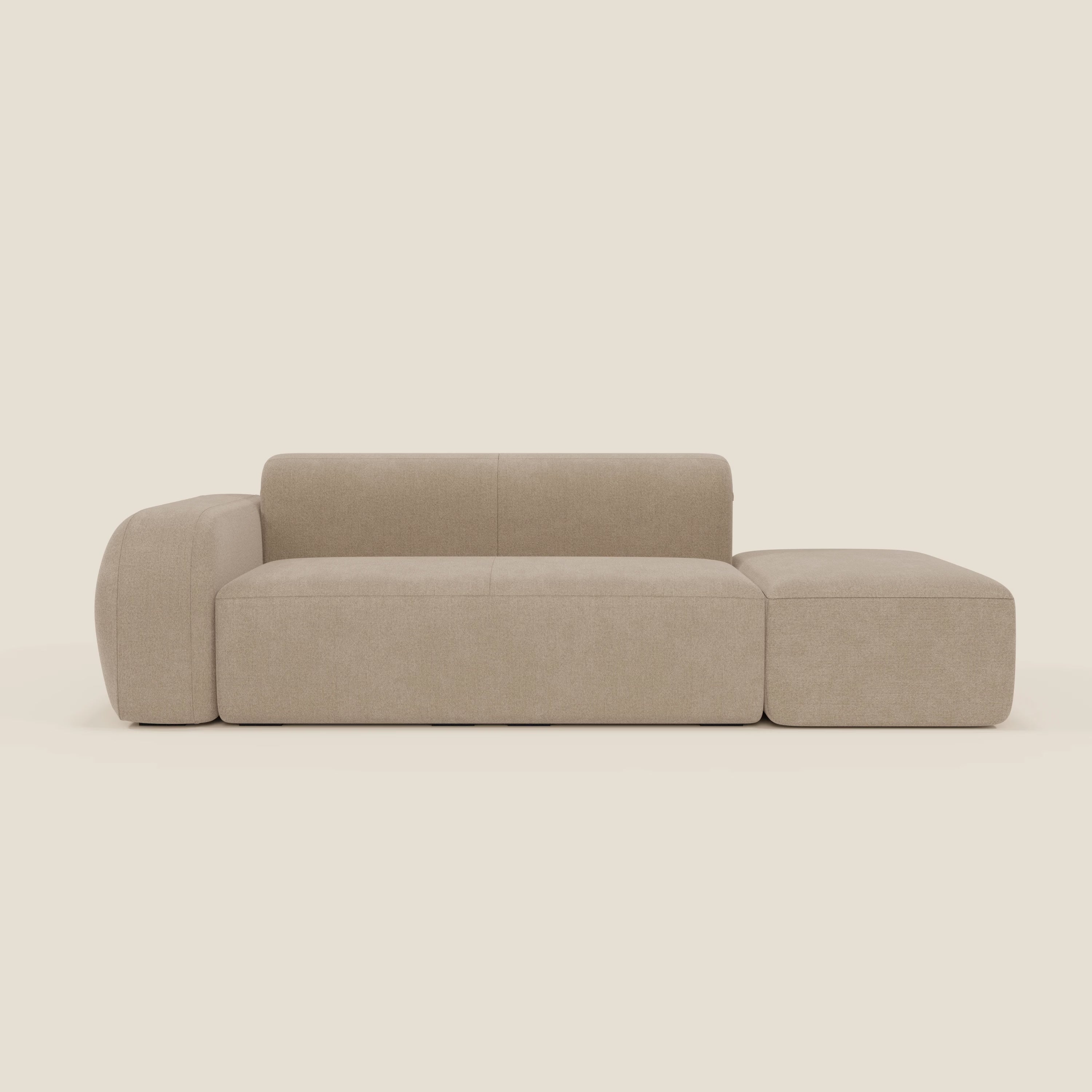 Il divano modulare componibile BonBon di Divani.Store, in tessuto smacchiabile beige T23, è caratterizzato da schienale basso, ampio bracciolo sinistro, pouf terminale destro e cuscini boxy in tessuto smacchiabile, su sfondo crema chiaro.