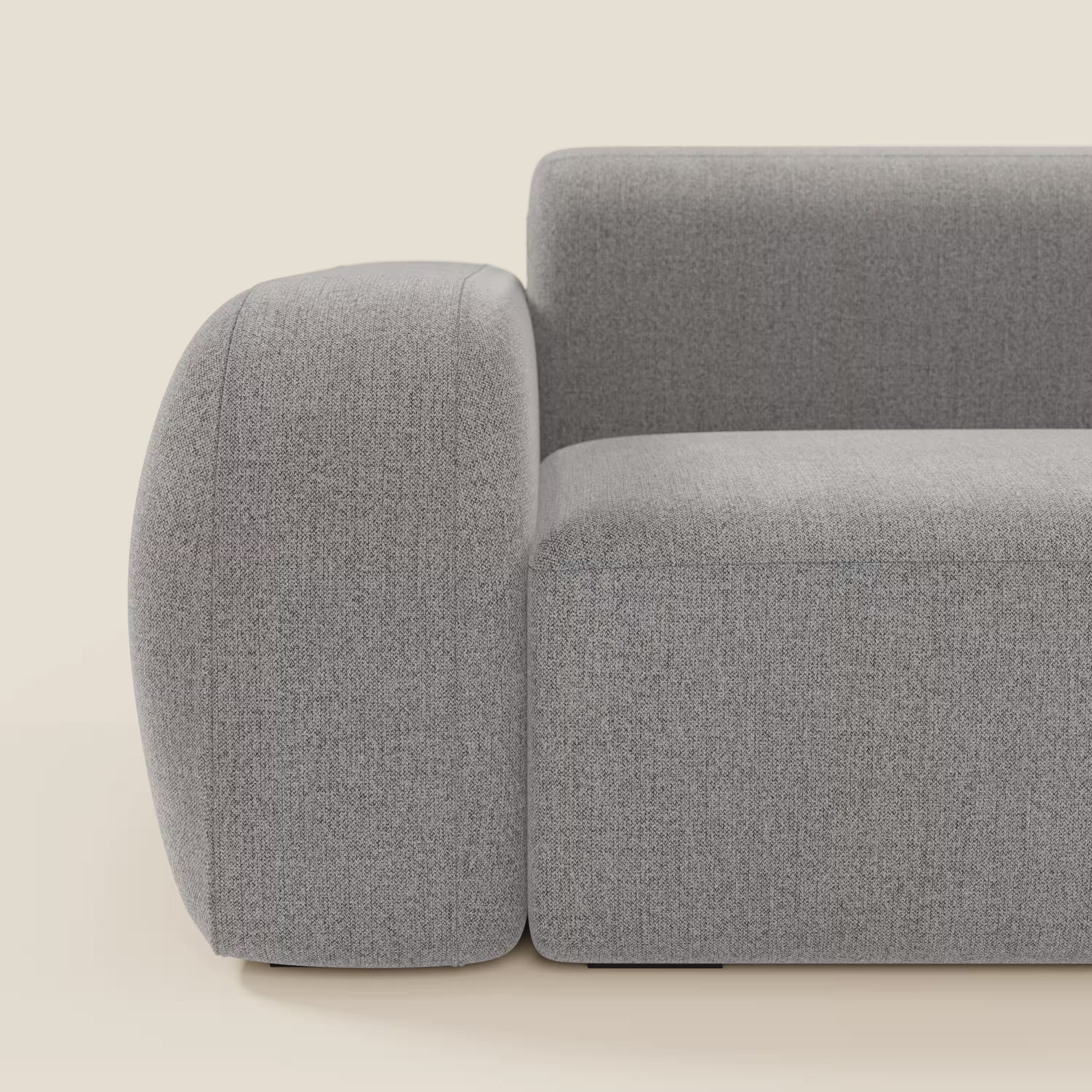 Vista laterale ravvicinata di BonBon Divano modulare componibile - Composizione con pouf terminale in tessuto smacchiabile T23 grigio di Divani.Store, caratterizzato da braccioli spessi e arrotondati, seduta squadrata e rivestimento in morbida texture in un design minimalista.