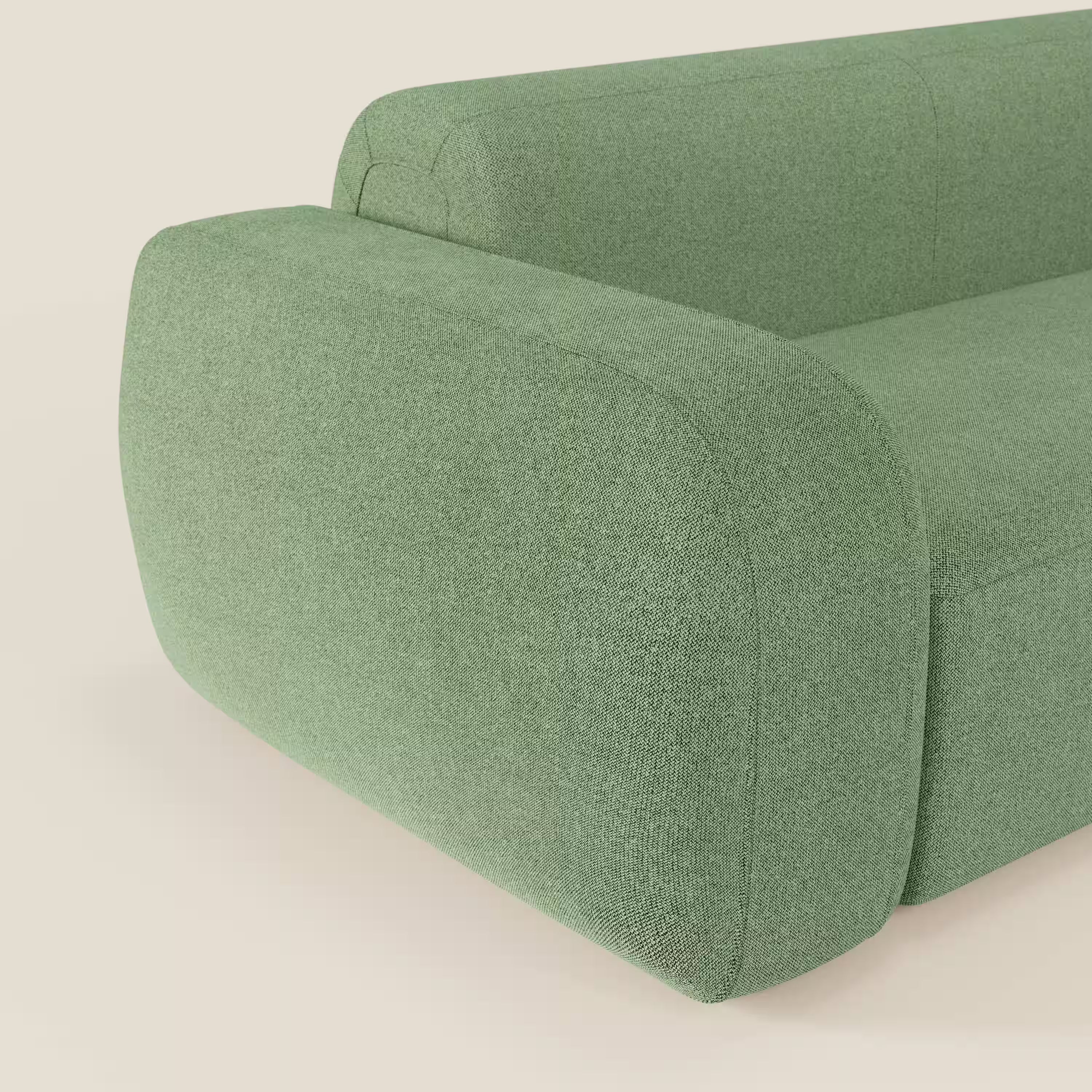 Primo piano del divano componibile BonBon Divano di Divani.Store, caratterizzato da bordi arrotondati e braccioli, rivestito in tessuto smacchiabile T23 menta. Il fondo beige chiaro mette in risalto il suo stile minimalista e contemporaneo con un pouf terminale.