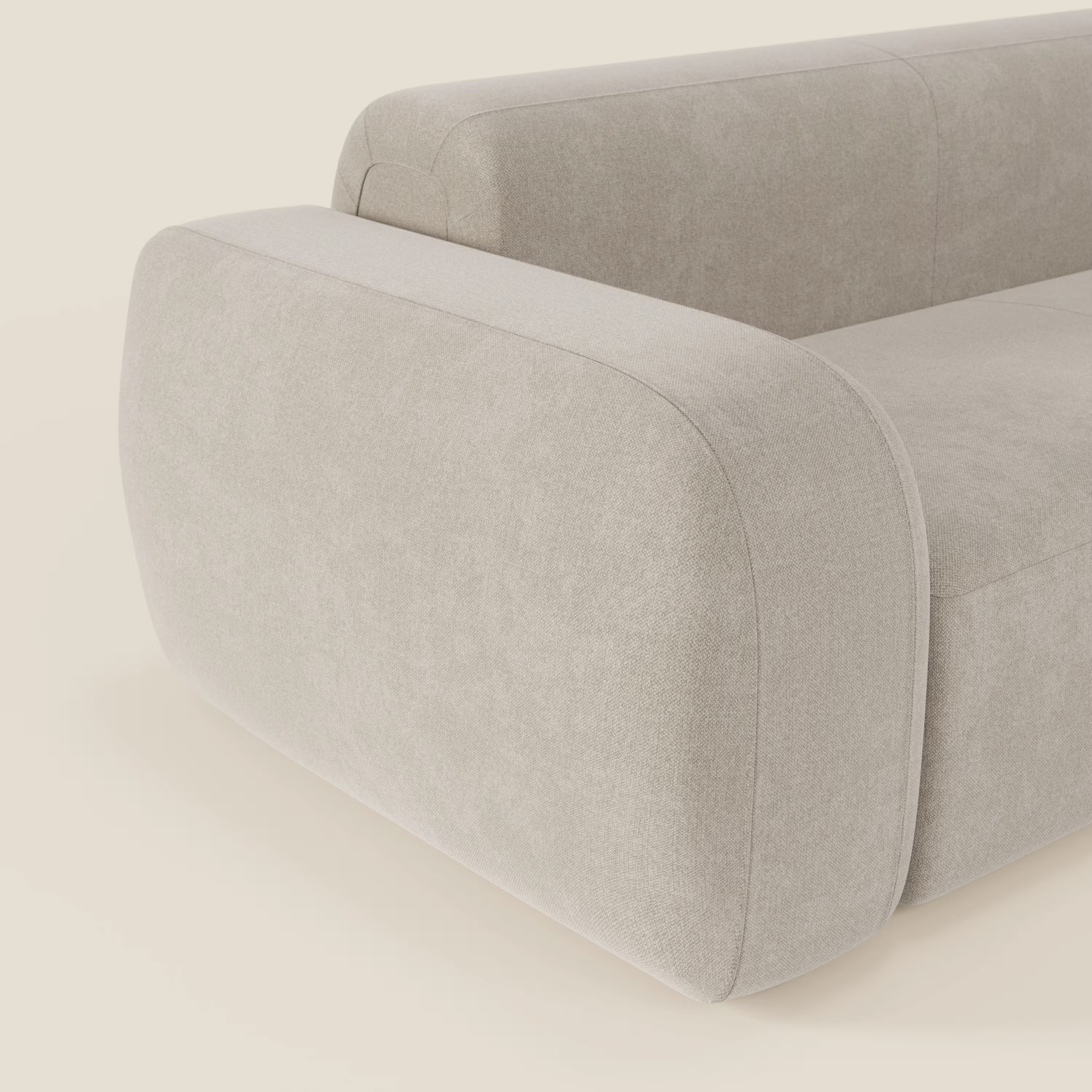 Un primo piano del BonBon Divano componibile - Composizione con pouf terminale in tessuto smacchiabile T23 panna di Divani.Store mette in evidenza il bracciolo sinistro in tessuto morbido, il rivestimento antimacchia e il design minimale e contemporaneo.
