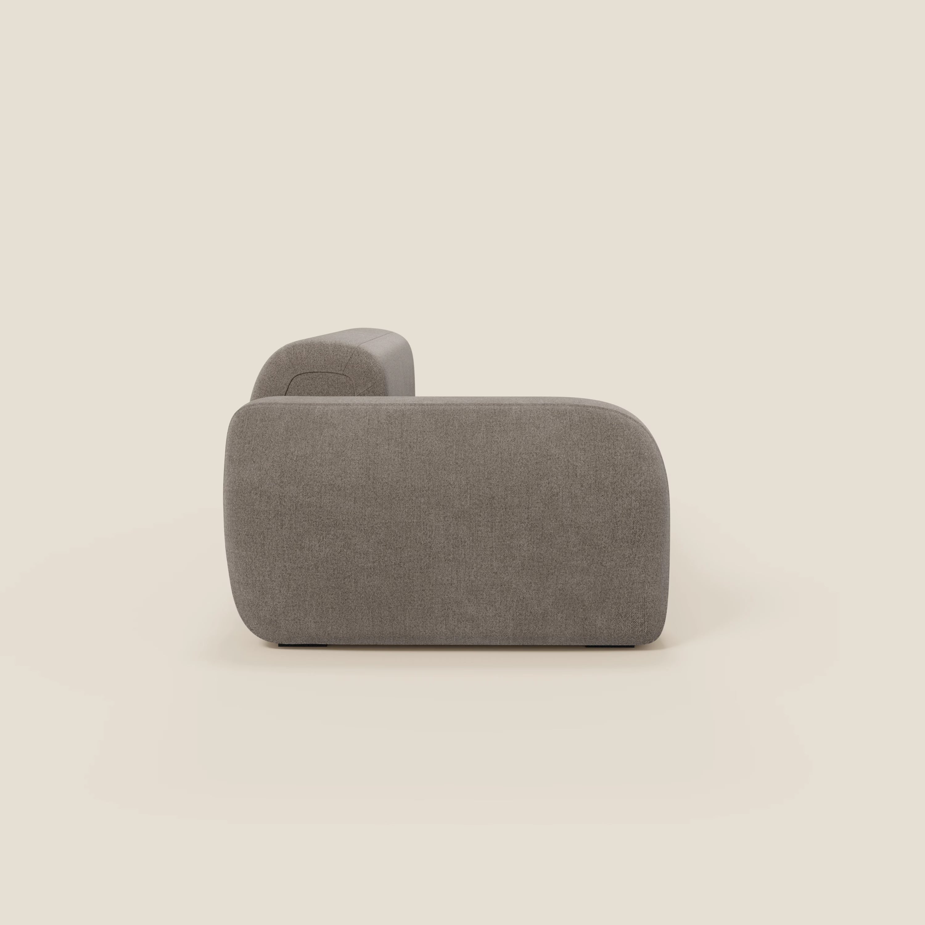 Il divano modulare componibile BonBon di Divani.Store è caratterizzato da un profilo basso e squadrato con bordi lisci e arrotondati e dal tessuto antimacchia T23 taupe, presentato lateralmente su uno sfondo beige chiaro con un pouf terminale.