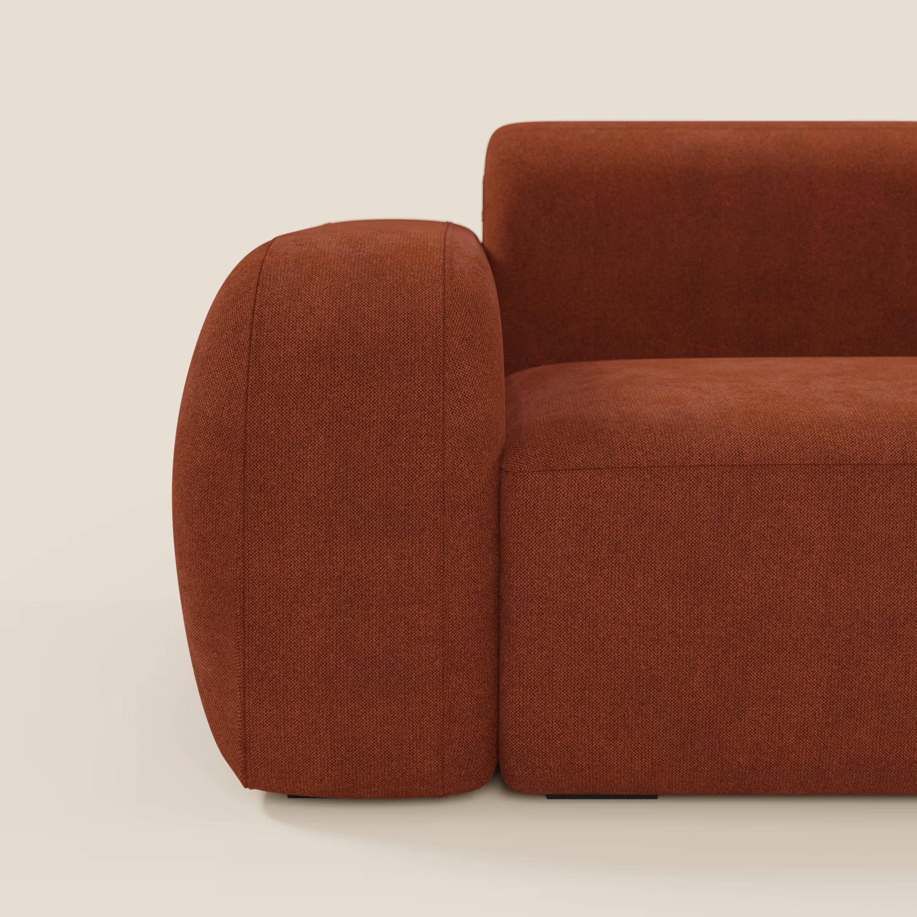 Primo piano del divano componibile BonBon Divano - Composizione Spaccamattone di Divani.Store, in tessuto antimacchia T23 ruggine, con braccioli spessi e arrotondati e un design minimale a blocchi, su sfondo crema.