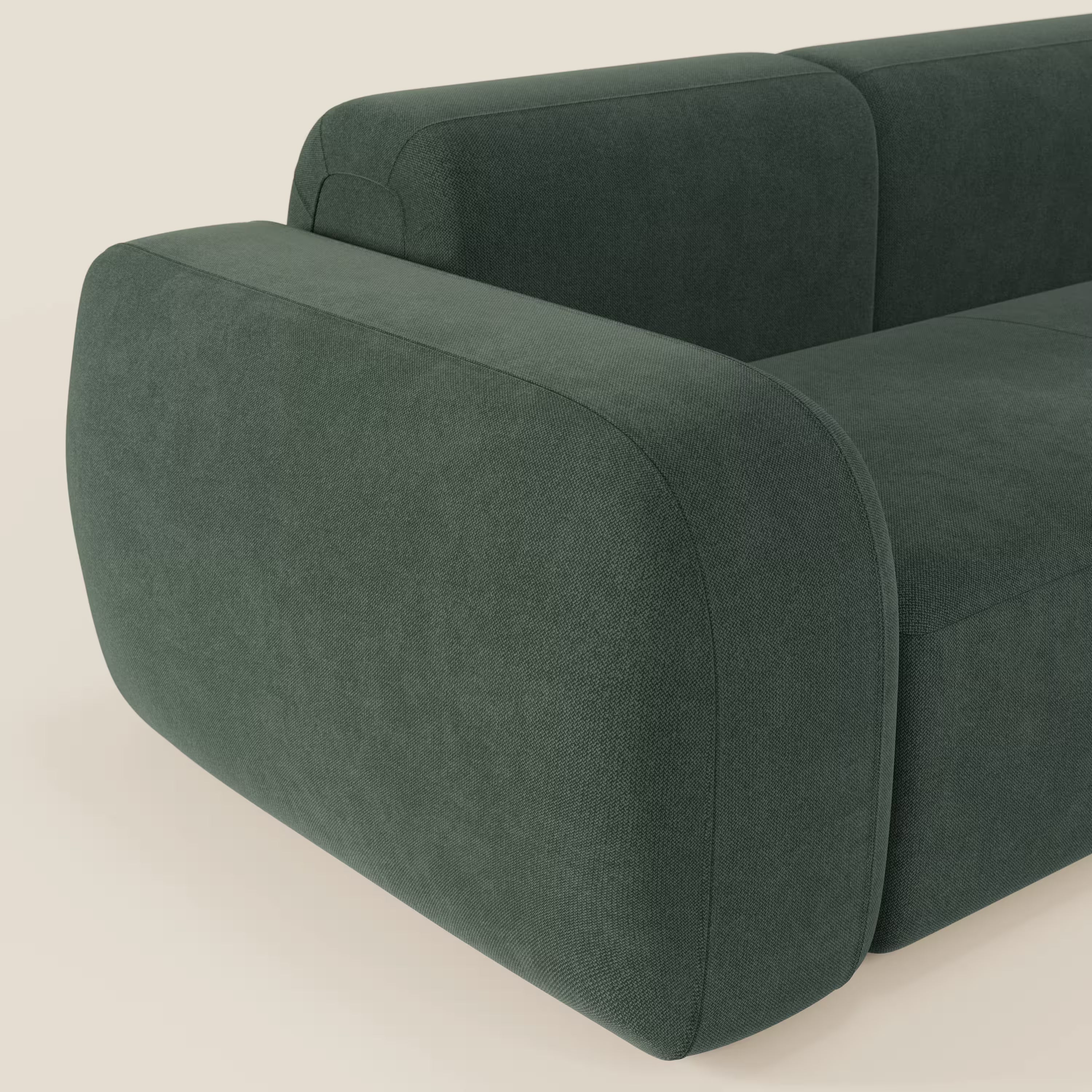 Un primo piano del BonBon Divano componibile - Composizione Spaccamattone di Divani.Store in tessuto antimacchia verde T23, con braccioli spessi e arrotondati e bordi morbidi, su uno sfondo neutro bianco sporco.
