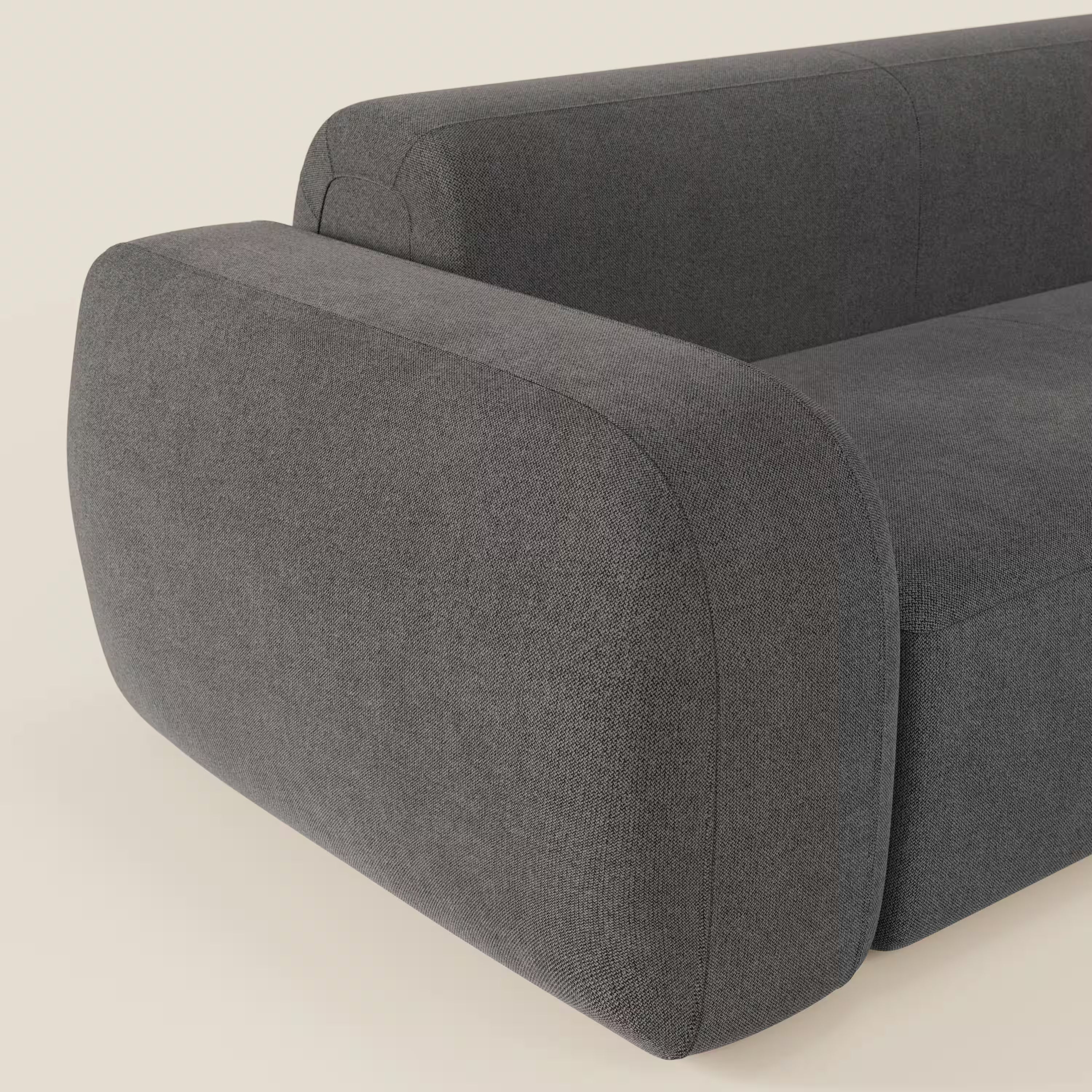 Primo piano del divano angolare componibile e modulare BonBon di Divani.Store in tessuto smacchiabile T23 antracite, con braccioli arrotondati, cuscini morbidi e sinuosi e un design minimalista su sfondo bianco sporco.