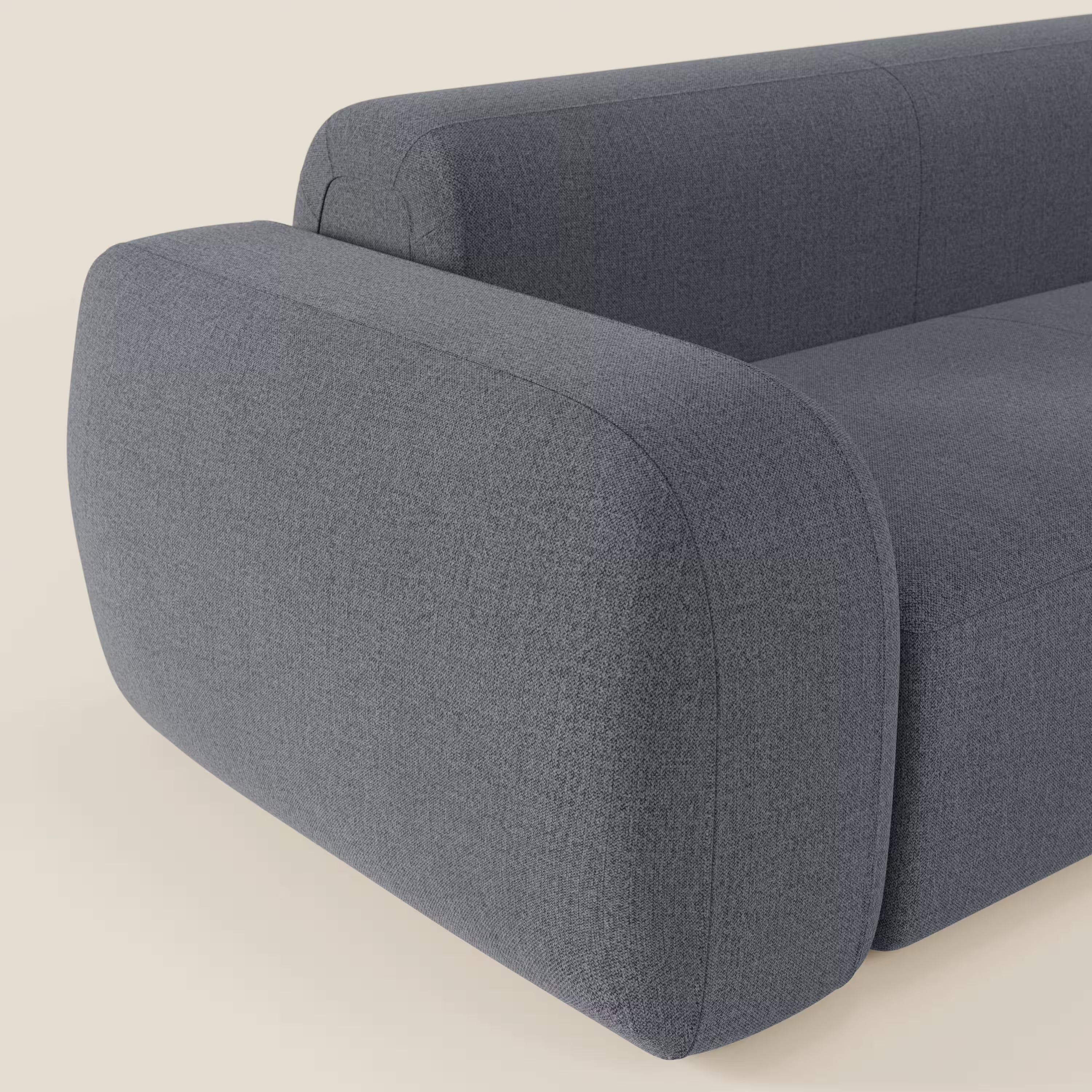 Primo piano del divano angolare componibile e modulare BonBon di Divani.Store in tessuto smacchiabile T23 blu grafite, caratterizzato da braccioli arrotondati e da un elegante design italiano su sfondo crema. Sono visibili solo parte dello schienale e un braccio.