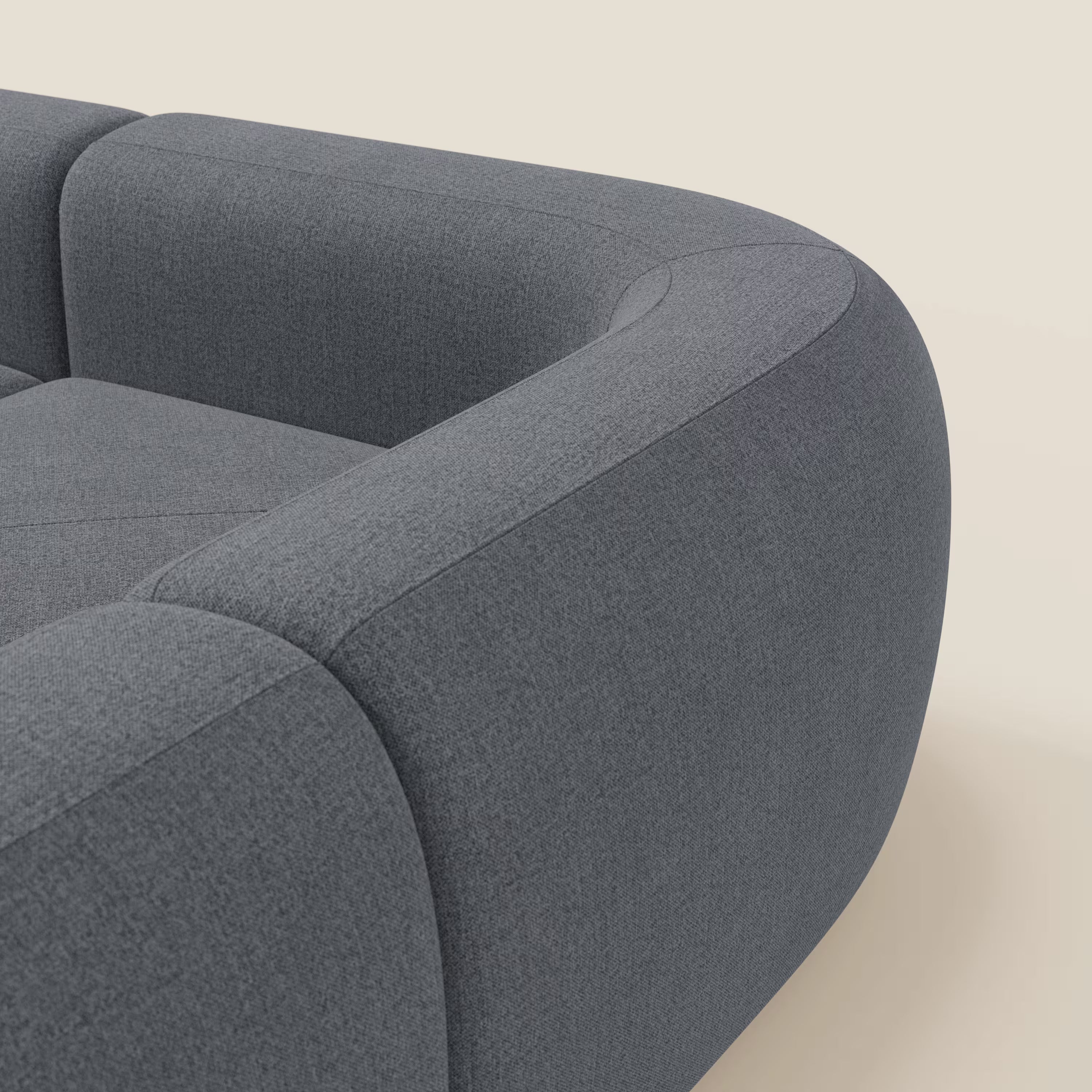 Primo piano del divano angolare componibile e modulare BonBon di Divani.Store, rivestito in tessuto smacchiabile T23 blu grafite, che mette in risalto il bracciolo e la seduta felpata con sottili dettagli di cucitura su uno sfondo beige neutro.