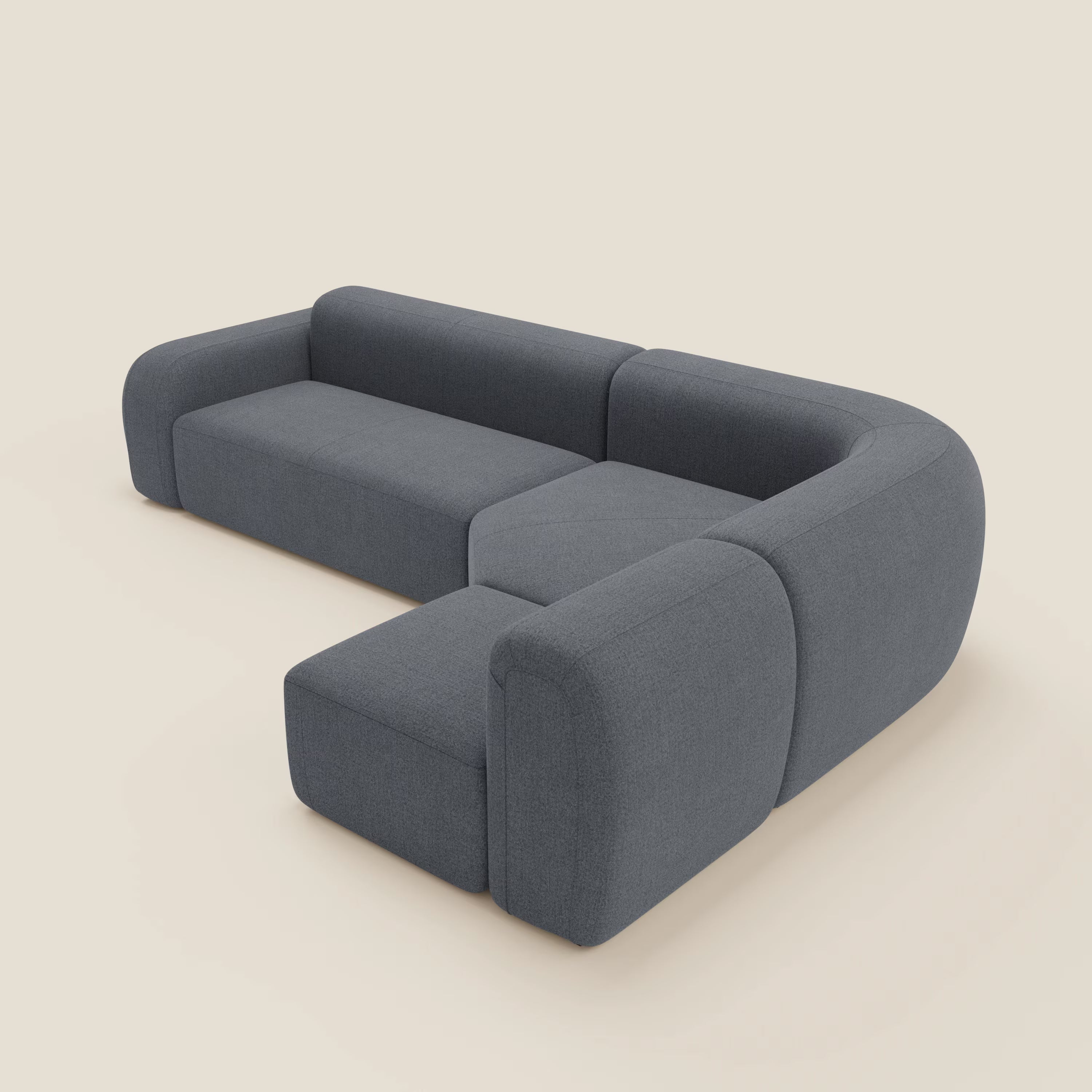 Il divano angolare componibile e modulare BonBon di Divani.Store, in tessuto smacchiabile T23 blu grafite, presenta linee moderne, bordi arrotondati e cuscini spessi su fondo beige chiaro.