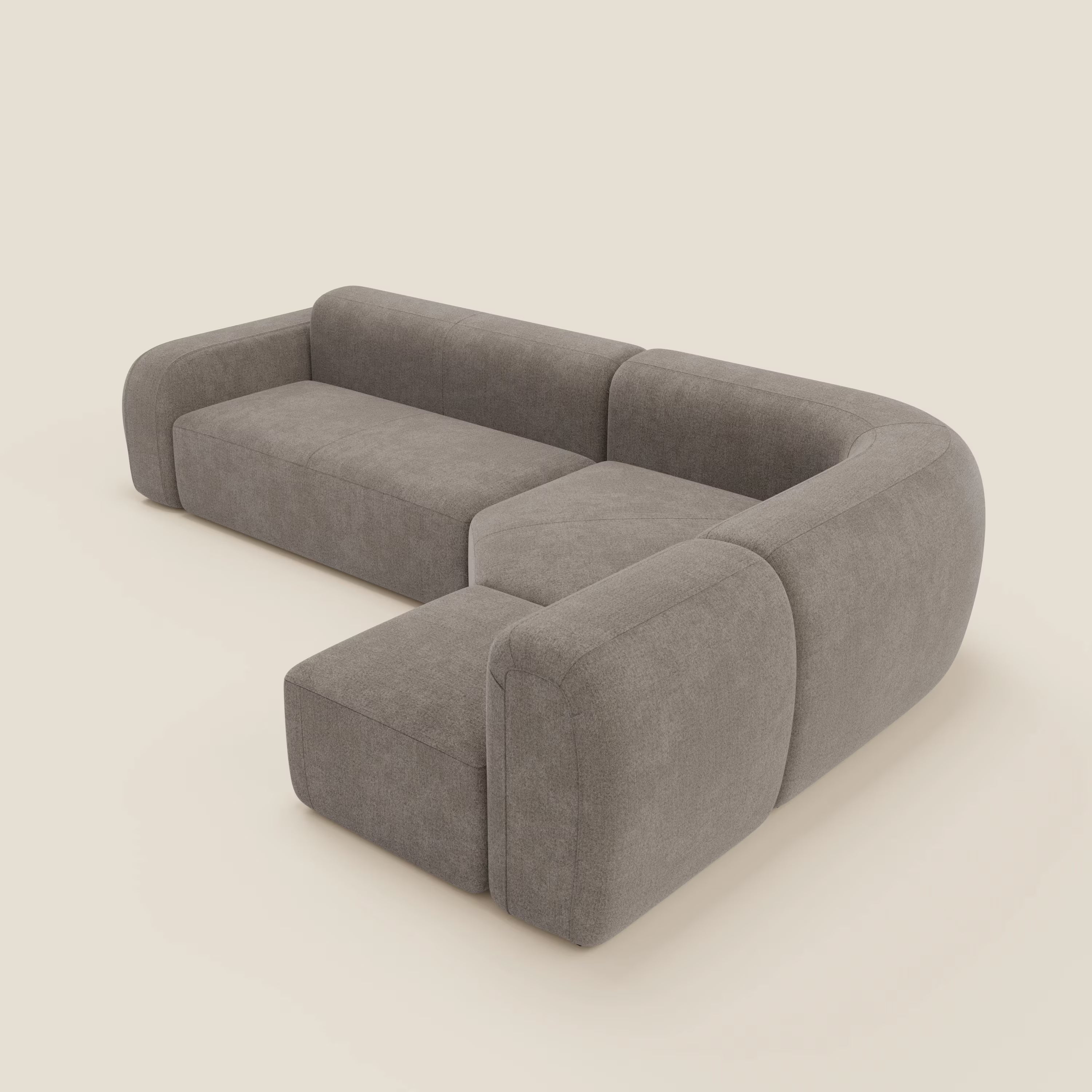 Il divano angolare componibile e modulare BonBon di Divani.Store, in tessuto smacchiabile T23 talpa, è caratterizzato da cuscini morbidi, angoli arrotondati e un design moderno e minimalista su uno sfondo beige chiaro.