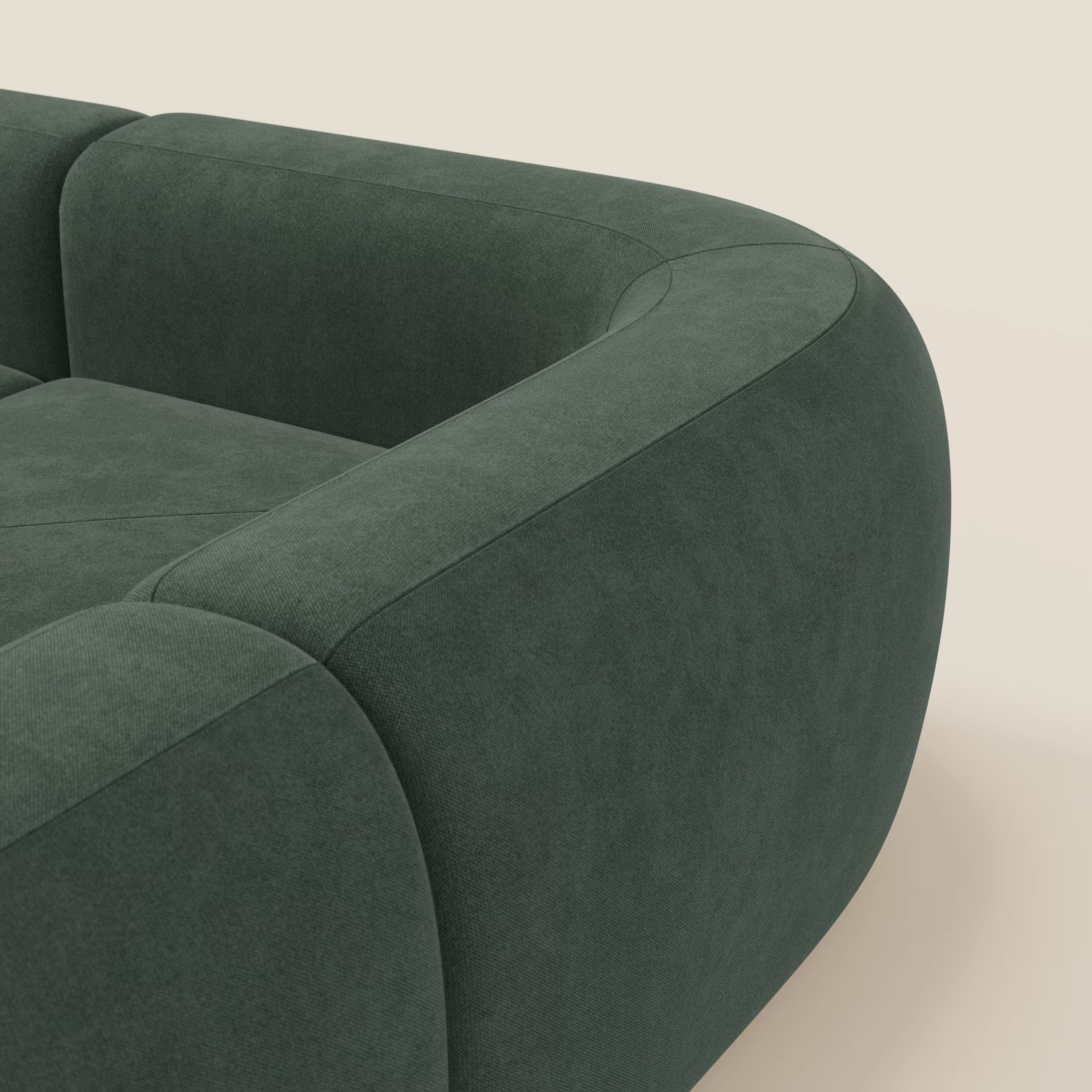Primo piano del divano angolare componibile e modulare BonBon di Divani.Store in tessuto antimacchia T23 verde, caratterizzato da braccioli e schienale arrotondati e morbidi con cuciture a vista, su sfondo beige chiaro. Prodotto in Italia.