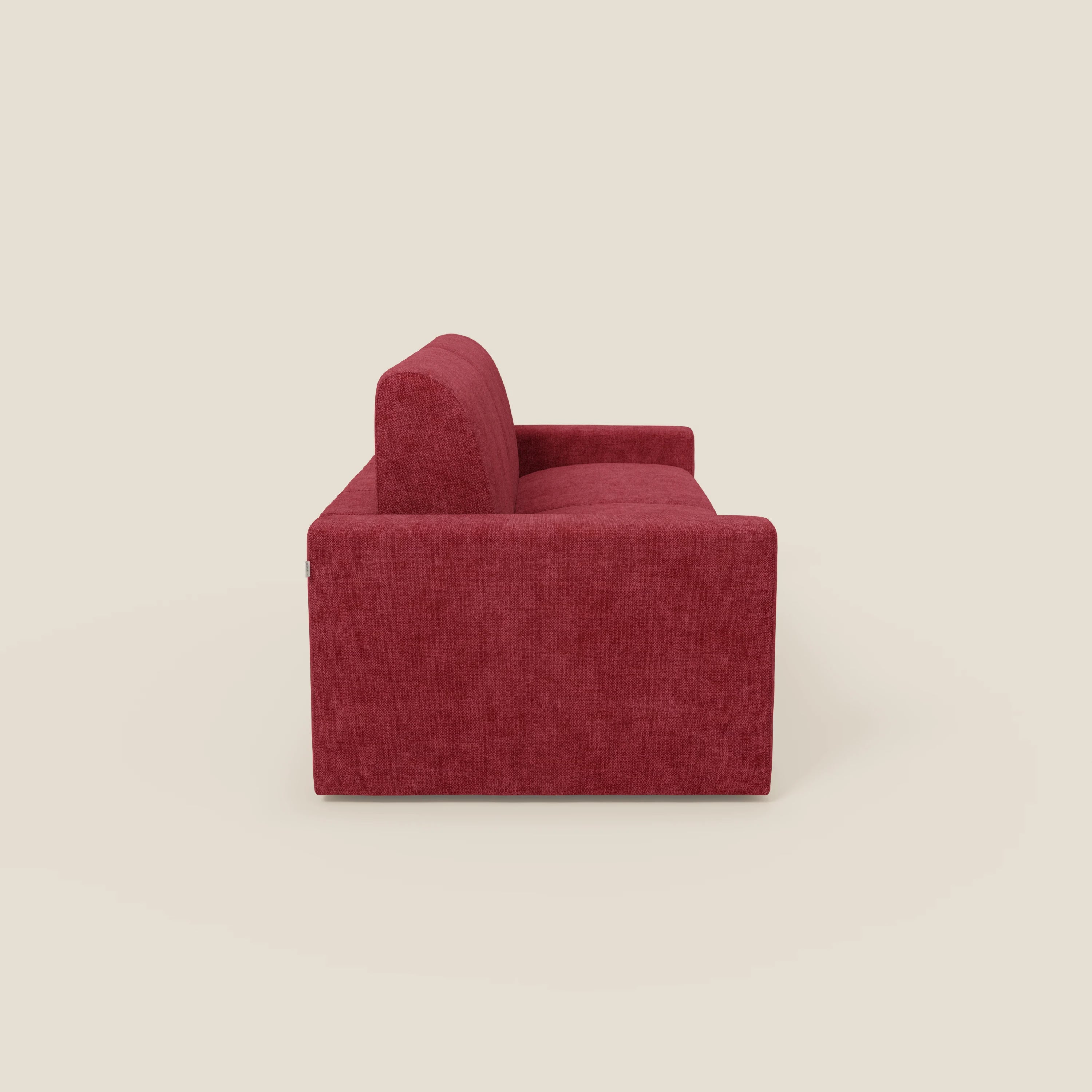 Vista laterale del divano letto matrimoniale Diomede in velluto easy clean T35 rosso di Divani.Store, caratterizzato da linee rette, cuscini spessi, braccioli bassi e rettangolari e un design squadrato e minimalista su uno sfondo beige chiaro.