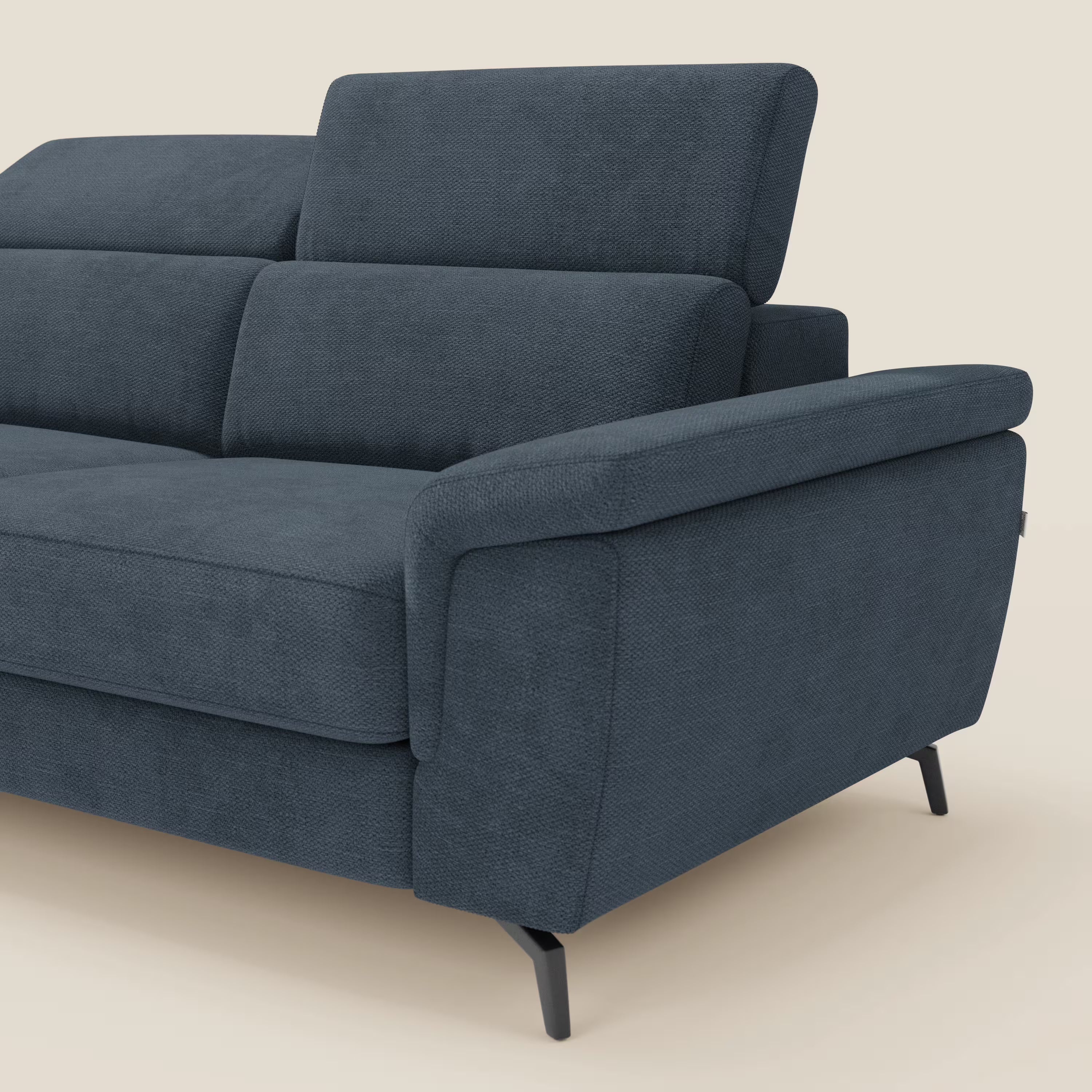 Estro di Divani.Store è un moderno divano in tessuto impermeabile blu con chaise longue, poggiatesta regolabile, ampio bracciolo e gambe in metallo nero. Presentato in un design pulito su uno sfondo beige chiaro, con un lato e parte della seduta visibili.