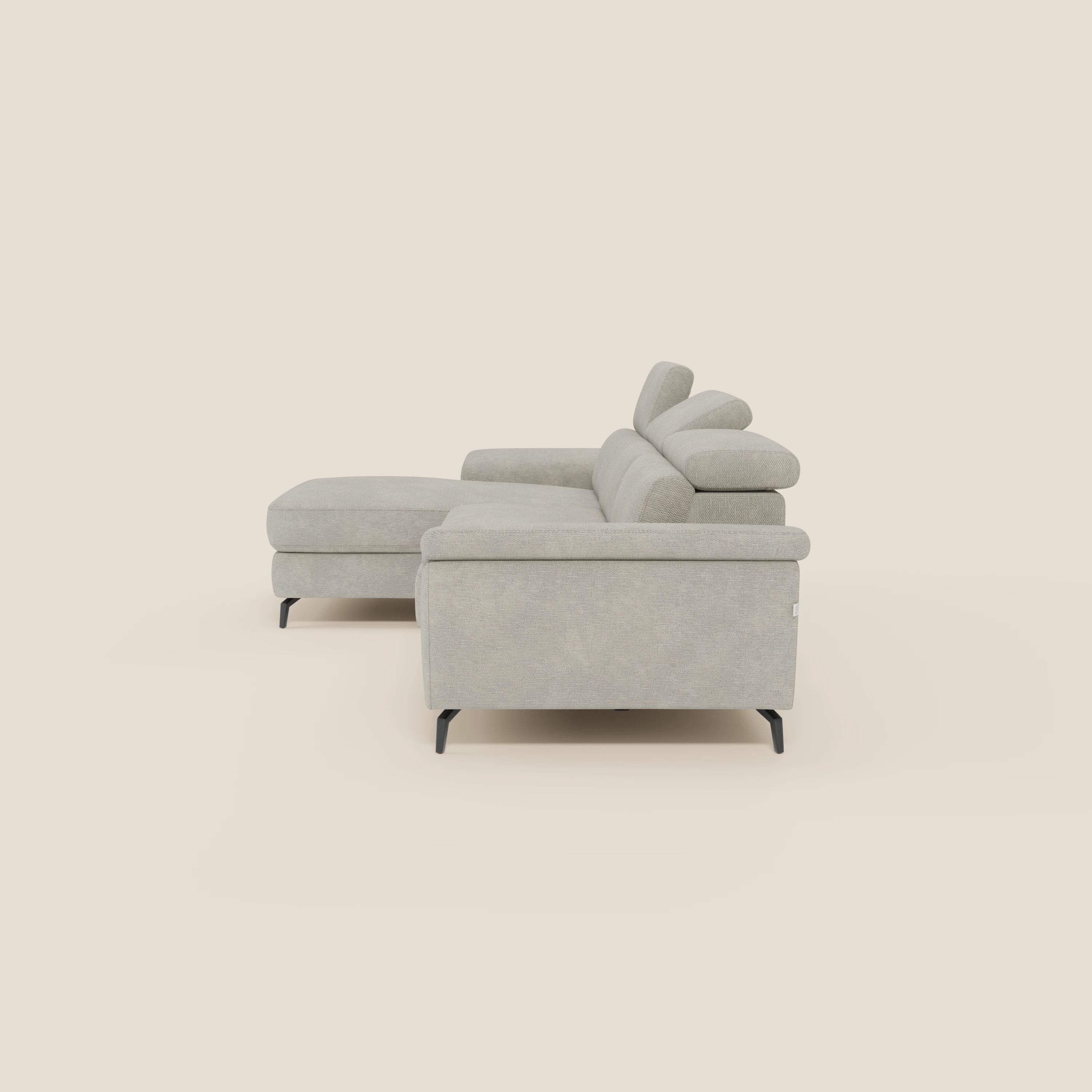 L'Estro Divano estraibile con chaise-longue e poggiatesta reclinabili in tessuto impermeabile T14 panna di Divani.Store è presentato lateralmente, evidenziando le sue linee minimali, il design contemporaneo e il colore crema chiaro.