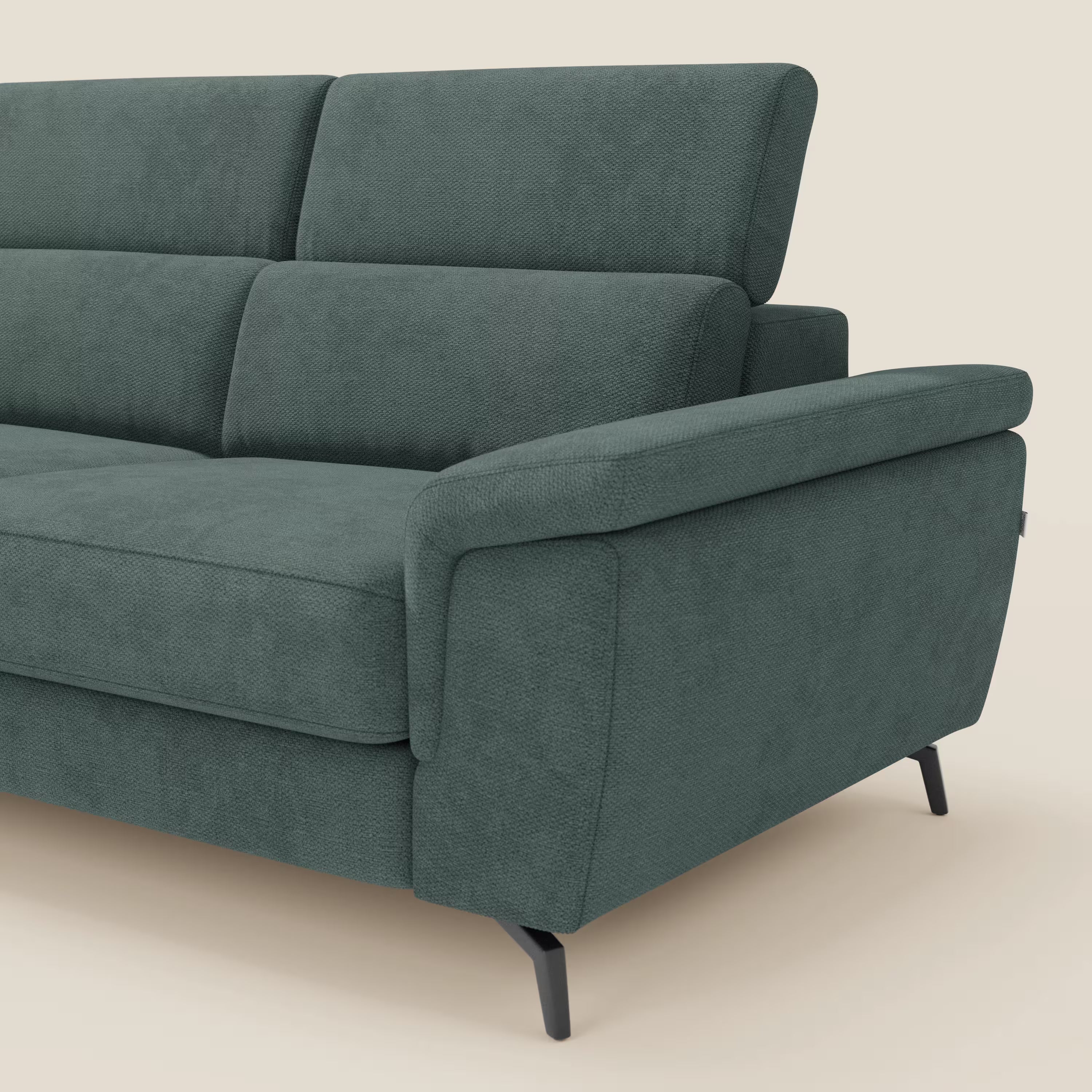 Un primo piano di Divani.Store Estro Divano angolare estraibile in impermeabile T14 verde mostra la seduta estraibile, la poggiatesta reclinabile, l'ampio bracciolo imbottito e le gambe in metallo nero su uno sfondo beige. Sono visibili solo un bracciolo e parte della seduta.