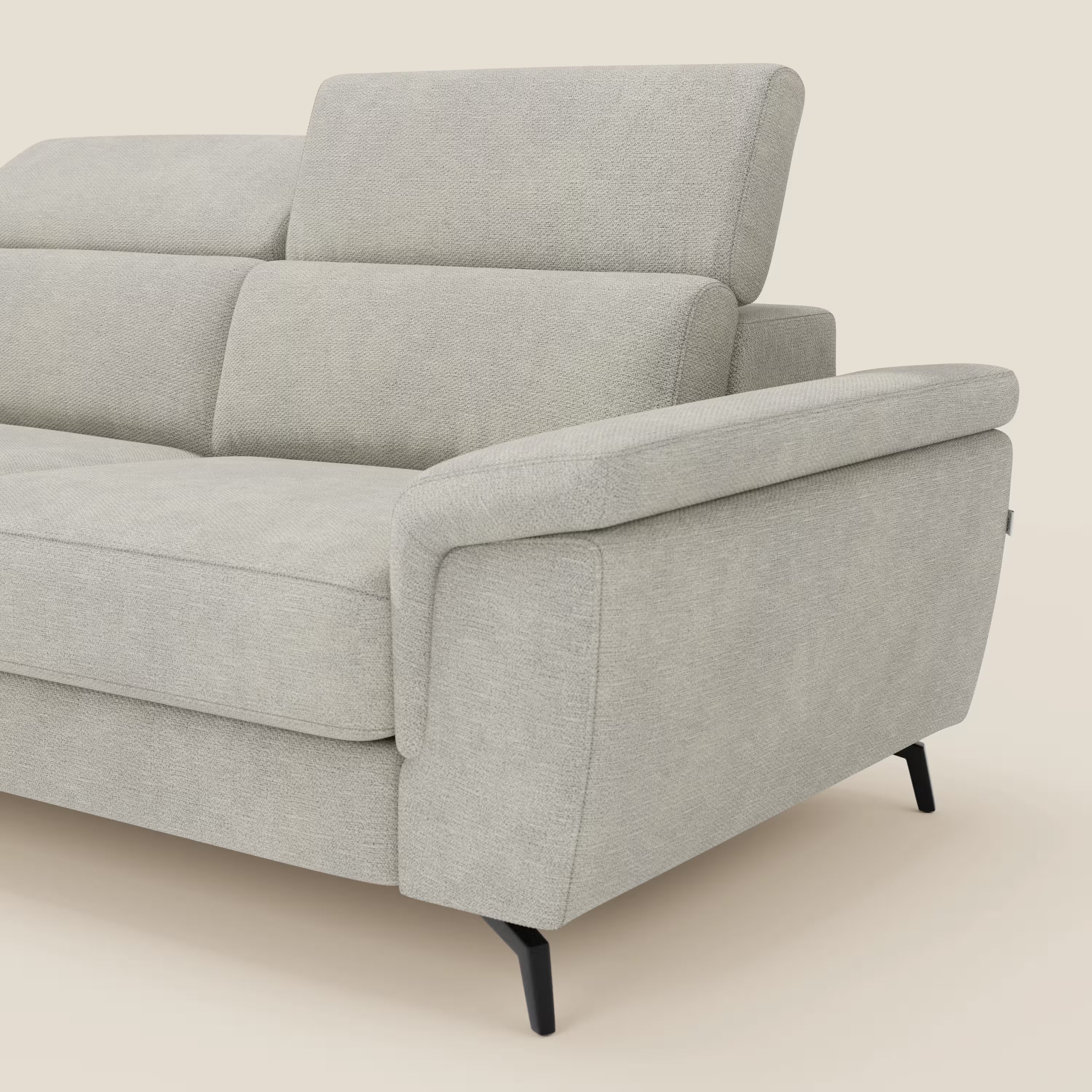 Un primo piano del divano a 3 posti Estro di Divani.Store con pouf estraibile, poggiatesta reclinabili e tessuto impermeabile T14 panna mostra solo il lato destro e parte dello schienale su un semplice sfondo beige.