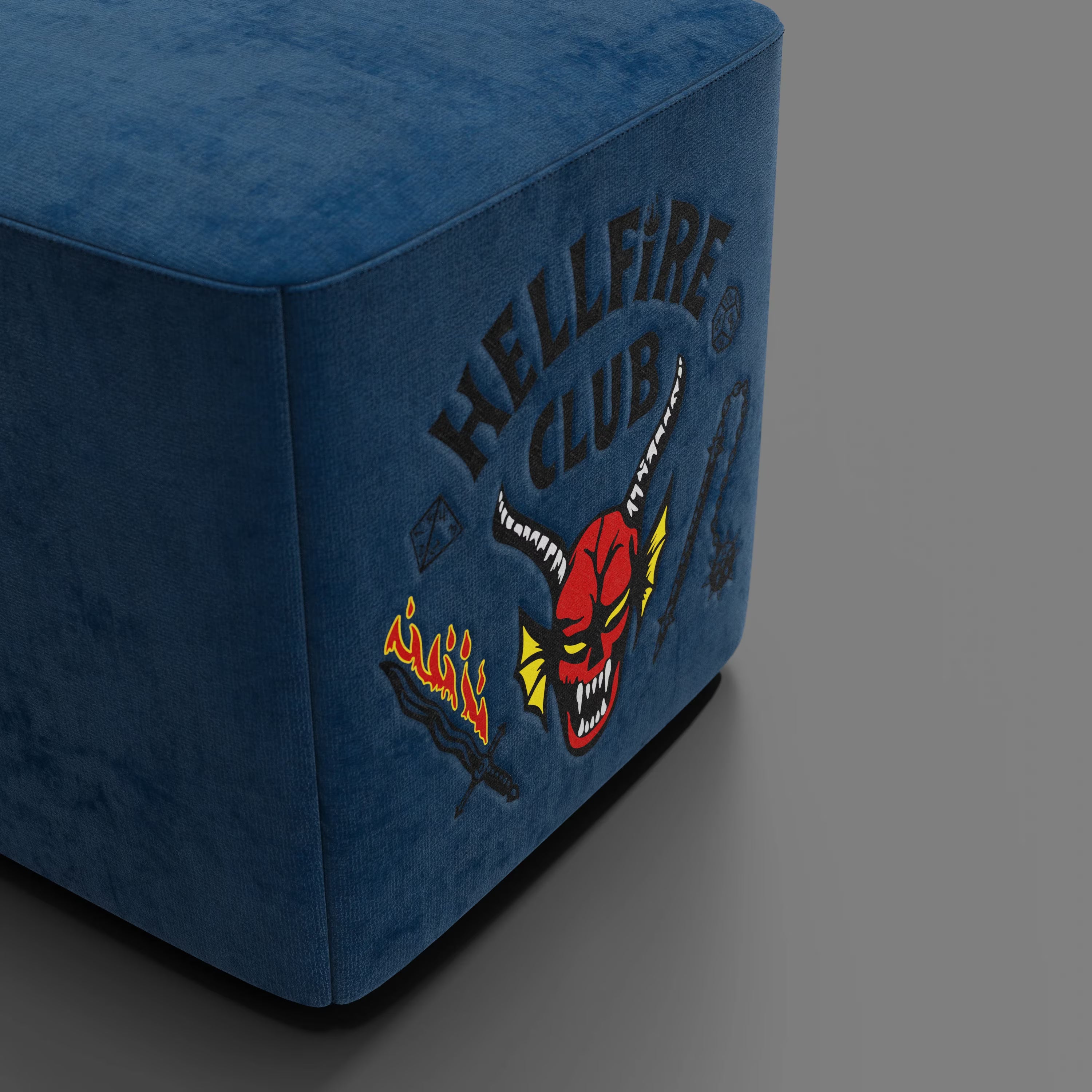 Il pouf Cube Hellfire club Stranger Things Edition di Divani.Store è un pouf blu con ricamo "HELLFIRE CLUB", faccia di diavolo rossa, spada fiammeggiante e dado, un'icona di design artigianale che si distingue in ogni ambiente.