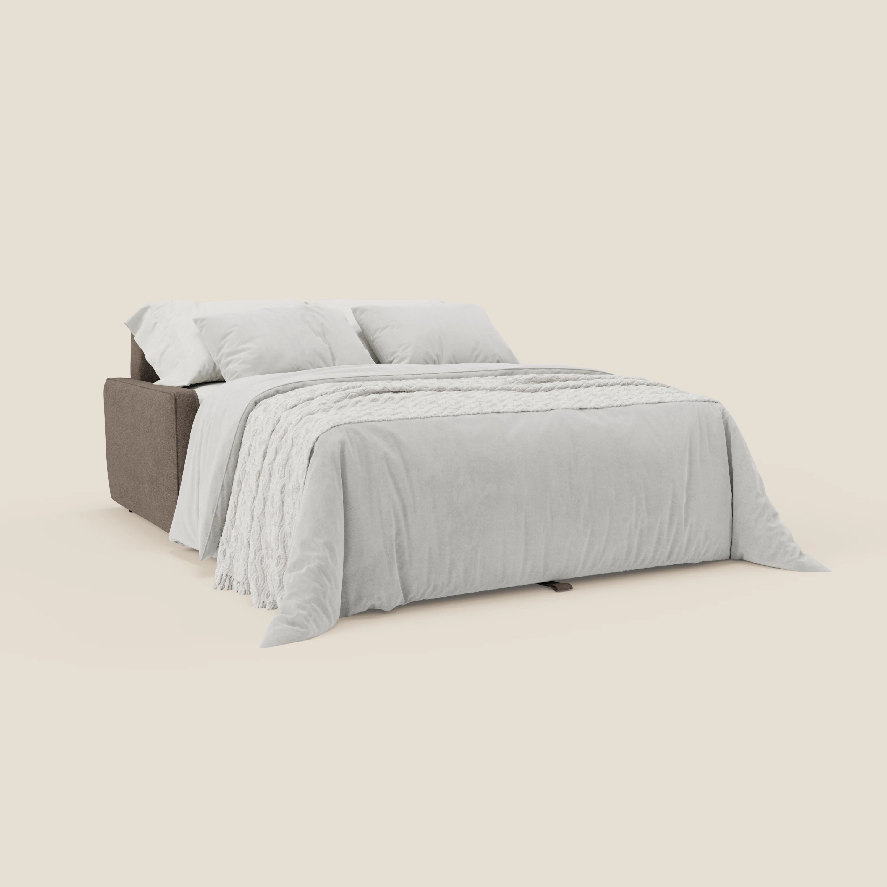 Il Nivon Divano letto moderno H16 cm di Divani.Store in T25 marrone si trasforma in un letto, arredato con un piumino grigio chiaro, una coperta con frange bianche e due grandi cuscini su uno sfondo beige.