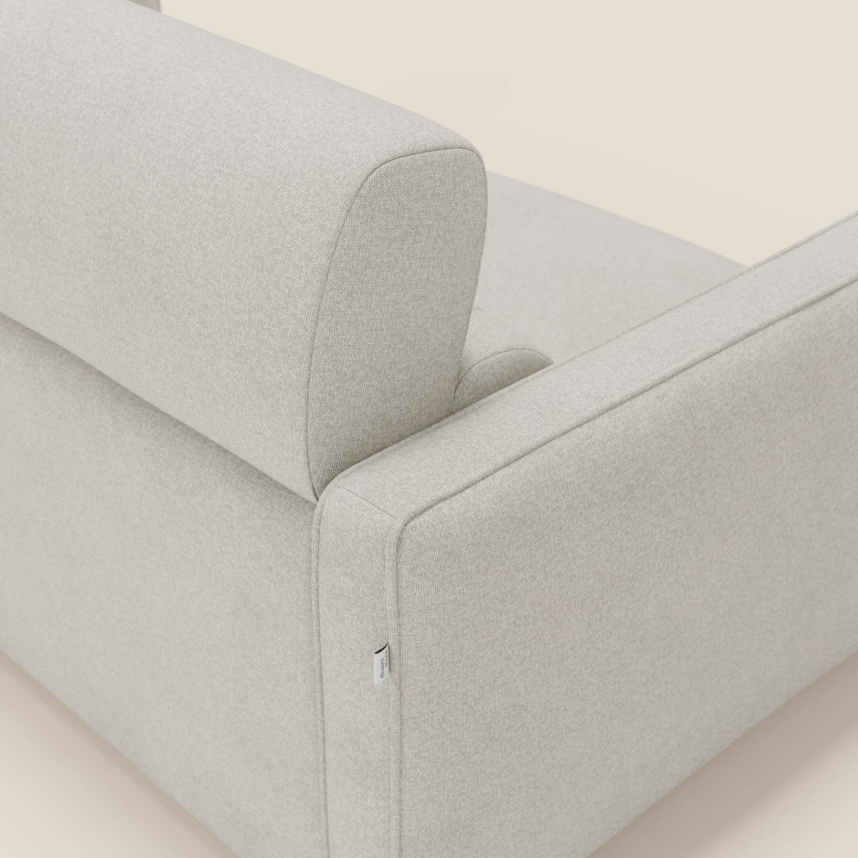 Primo piano del divano letto moderno Divani.Store Nivon H16 cm in tessuto impermeabile T25 panna, che mette in evidenza l'elegante bracciolo, lo schienale e la targhetta in tessuto. Su uno sfondo beige neutro, per un comfort e uno stile moderni.